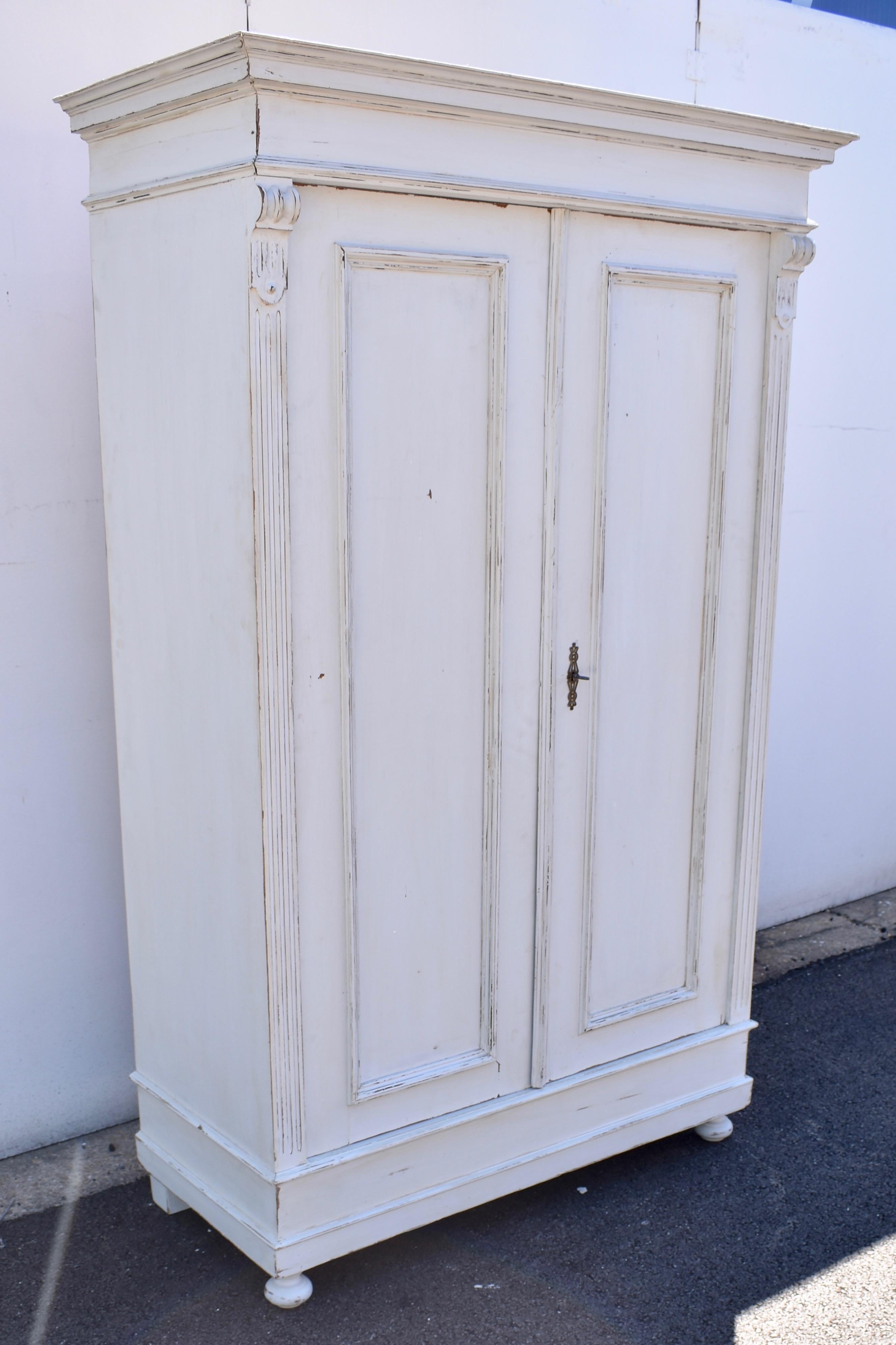In its classic late nineteenth century German form, this oak armoire has a bold crown molding and frieze above two pivot-hinged flat paneled doors, with applied fluting and corbels on the front corners. The interior has a single shelf above a
