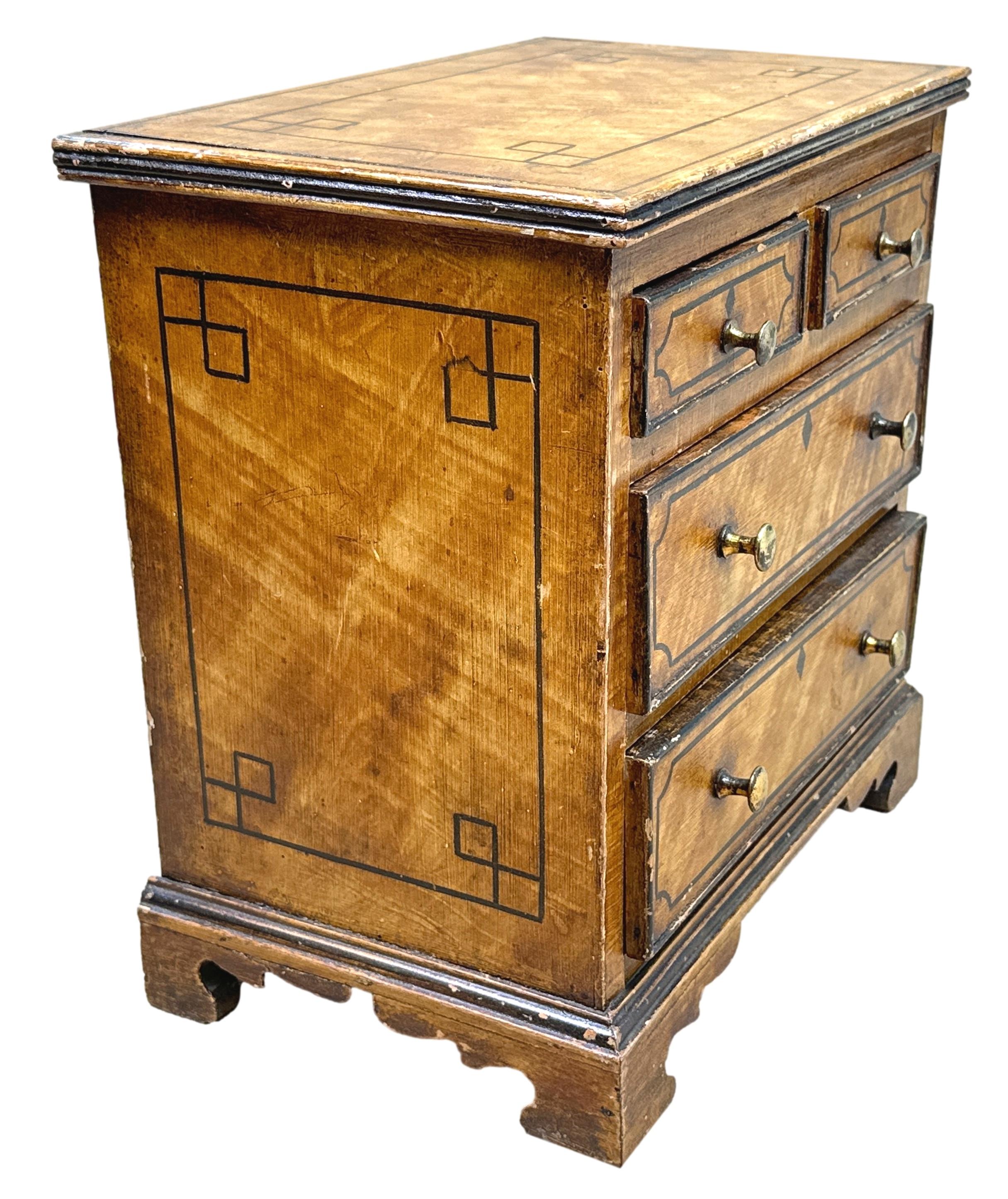 Un'elegantissima cassapanca in miniatura in pino dipinto della metà del XIX secolo, con eleganti decorazioni sulla parte superiore e sui lati, con due cassetti corti e due lunghi che conservano i pomelli originali in ottone tornito, sollevati su