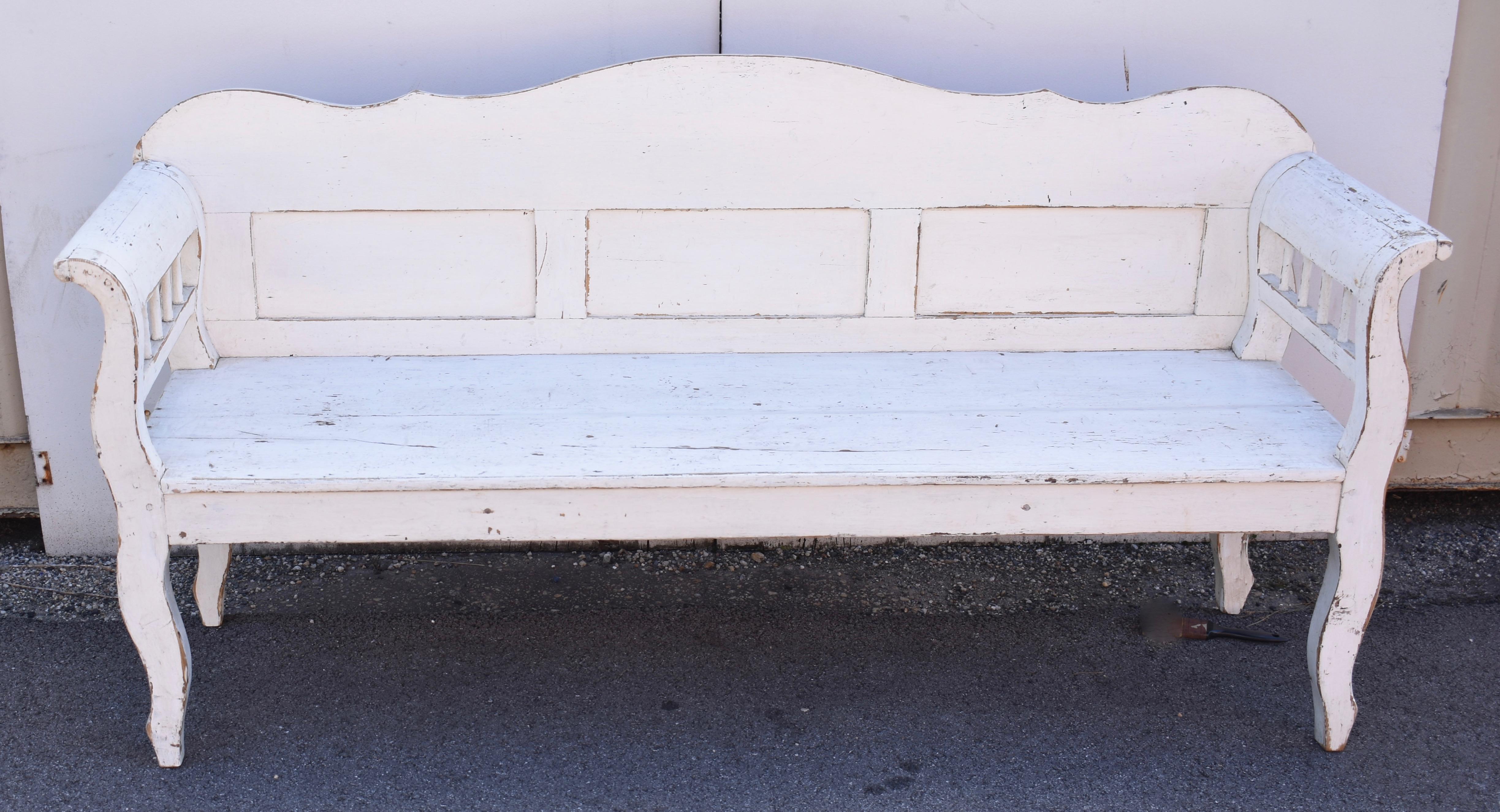 This bench, although very sturdy, looks light enough to dance, perched as it is on its tiptoes, on the ends of its shapely cabriole legs.  The curve in the leg is repeated as it moves up and becomes the boldly scrolled arm.  The back has a gentle