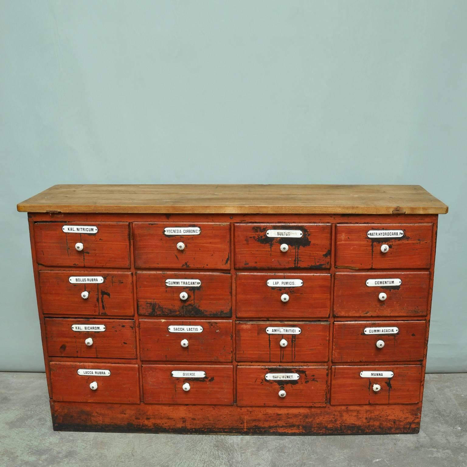 In largely original condition, the red painted apothecary cabinet with 16 drawers each with porcelain knob handles and enamel labels.

In part-restored condition, the painted pine drawer fronts are worn, with a well established patina. The cabinet