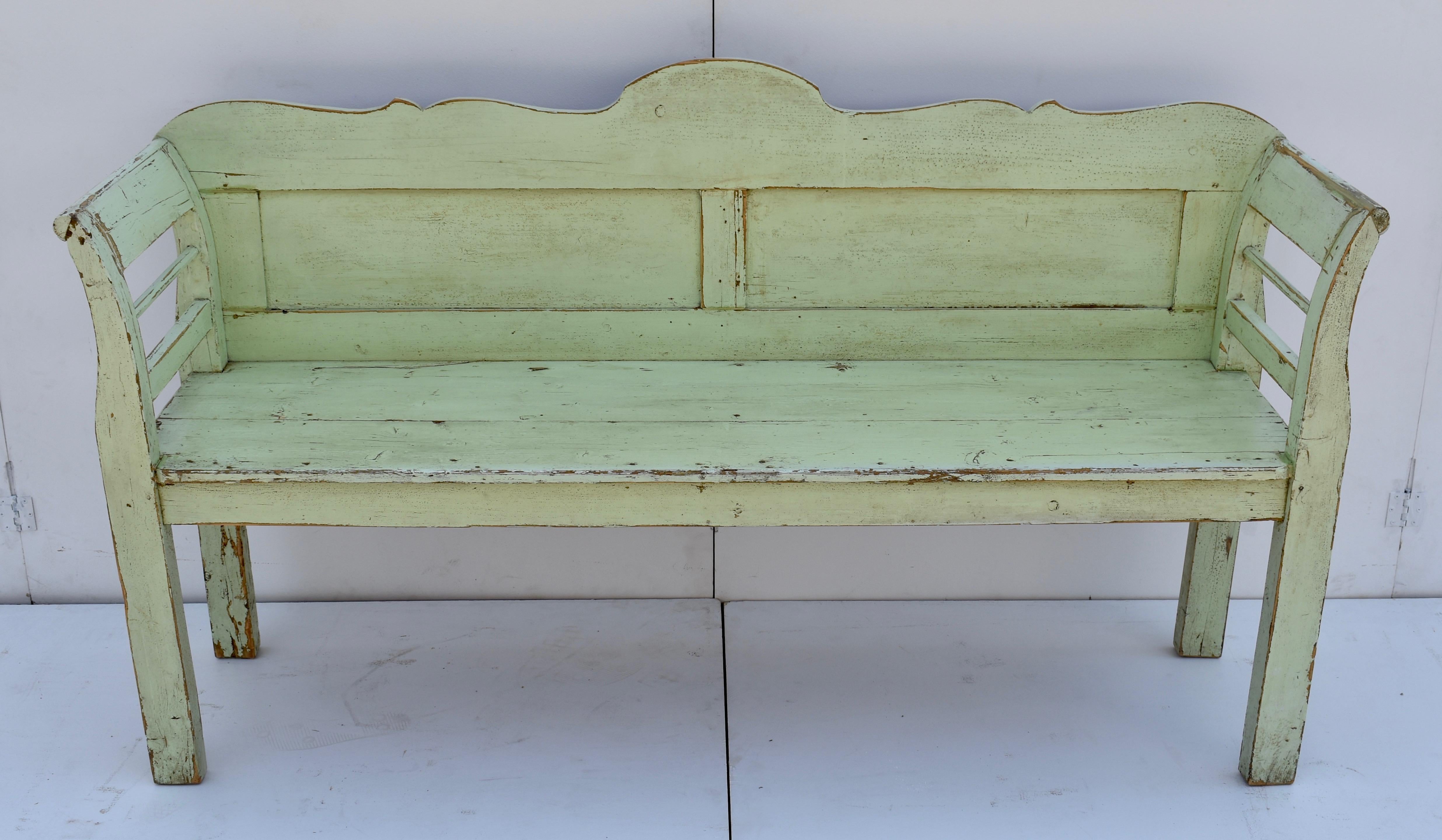 This lovely painted bench has a nicely scalloped top rail above two enclosed flat panels. The integral scrolled arms and rectangular legs support a seat which is conveniently shallower than most yet still comfortable. A classic Central European form