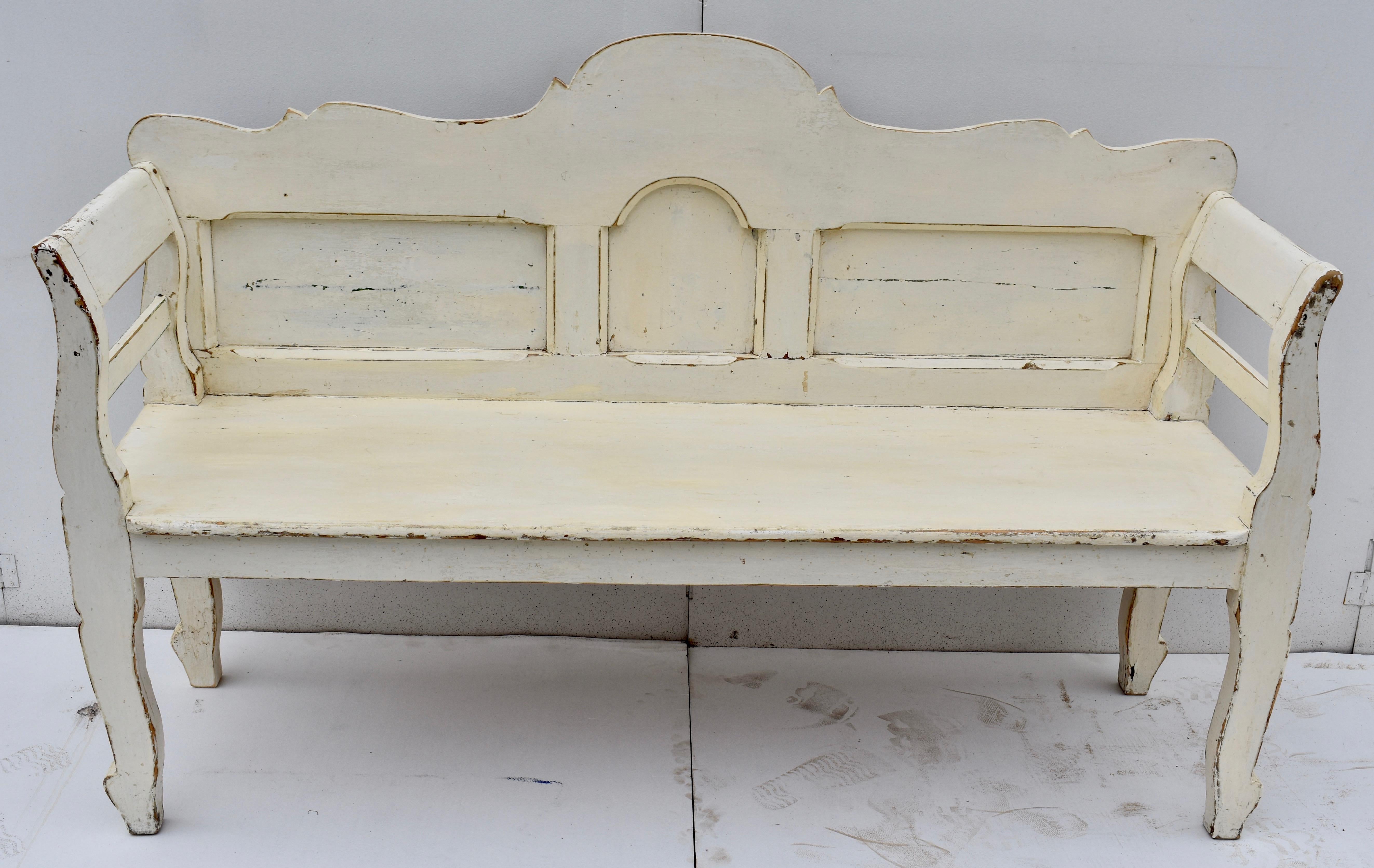 This sturdy bench has a terrific form. Its scalloped back rail has a high central dome, gently undulating on each side. A small arched panel is flanked by two long rectangular panels with the rails and stiles of the back nicely chamfered at their