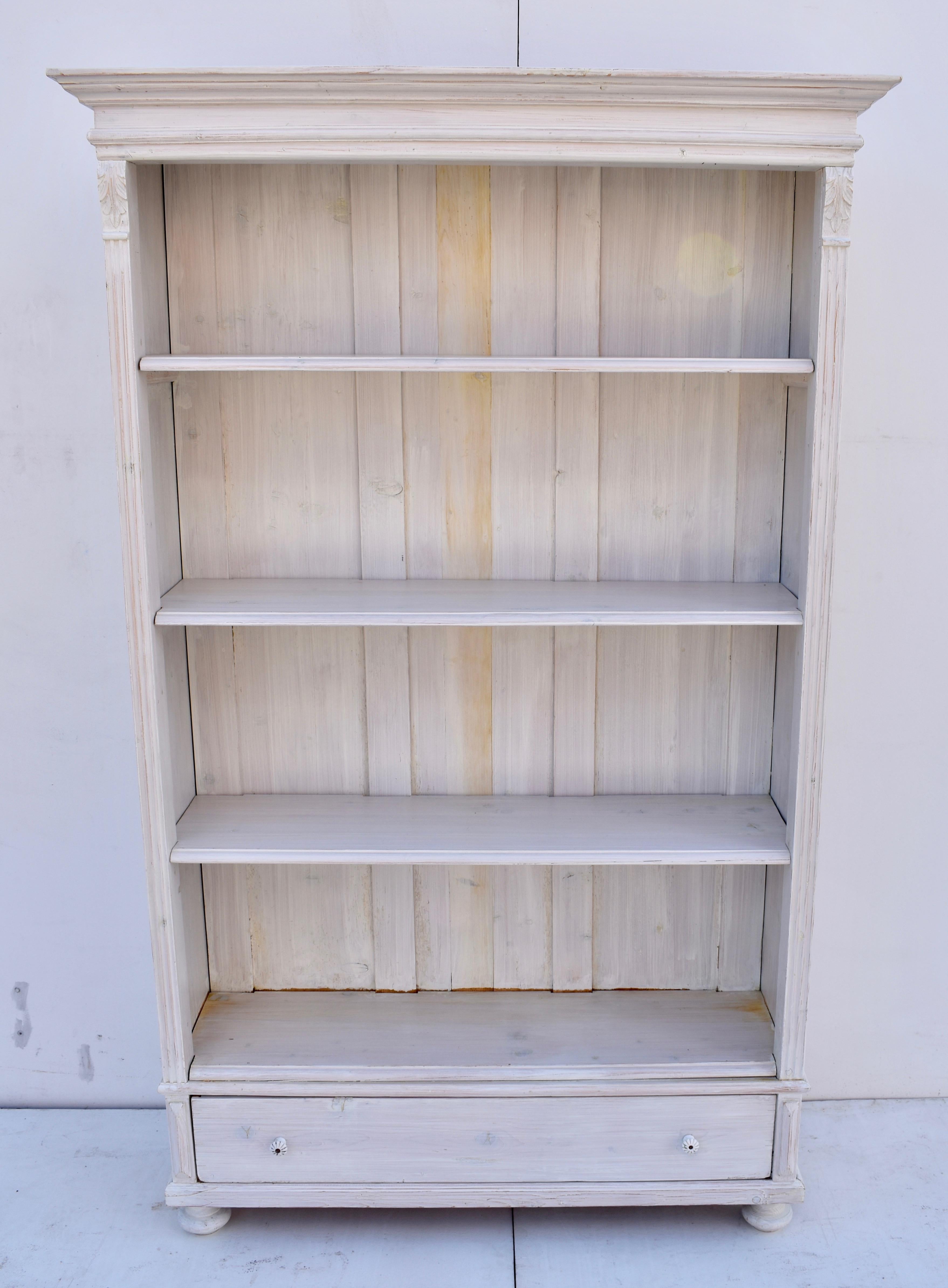 Antique pine bookcases are hard to find so the shell of this piece was provided by a vintage pine armoire which had suffered some damage or perhaps lost a door. With one board width removed from the sides and the original backboards and crown