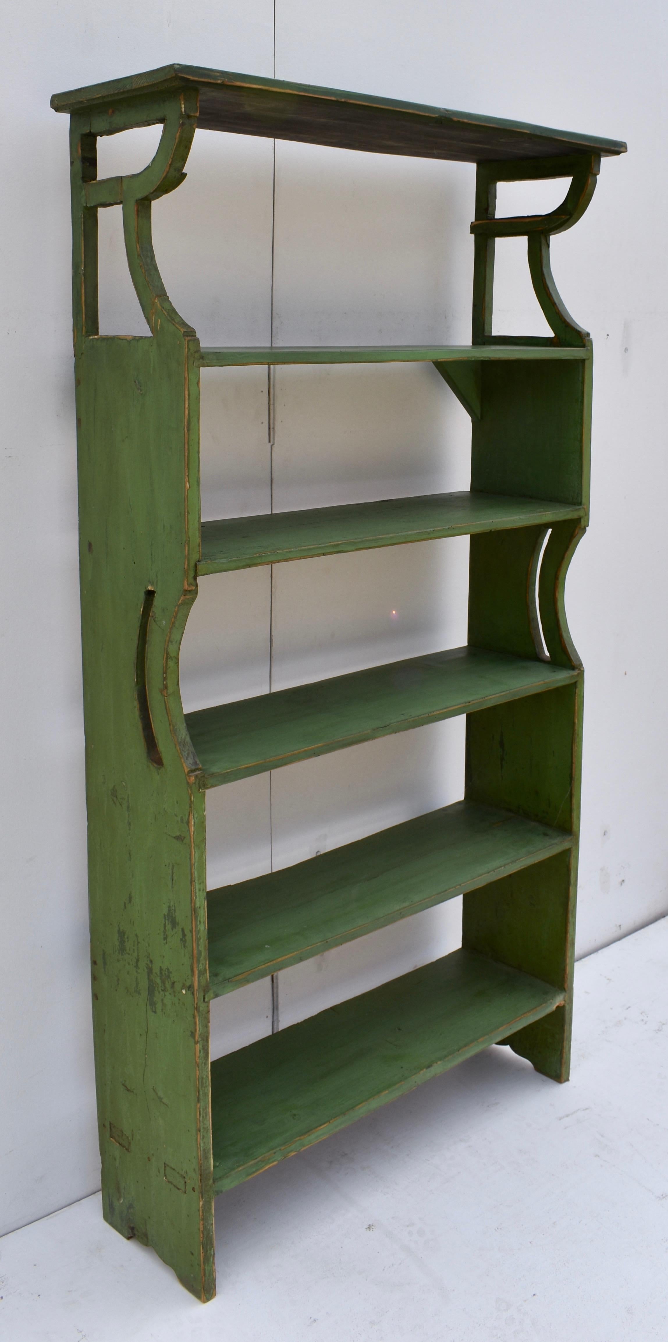 This narrow and low profile run of shelves offers four more or less equal spaces for books or pots and pans, and a larger space at the top, perhaps for display. It is built to withstand weight, with the bottom shelf through-tenoned and the other