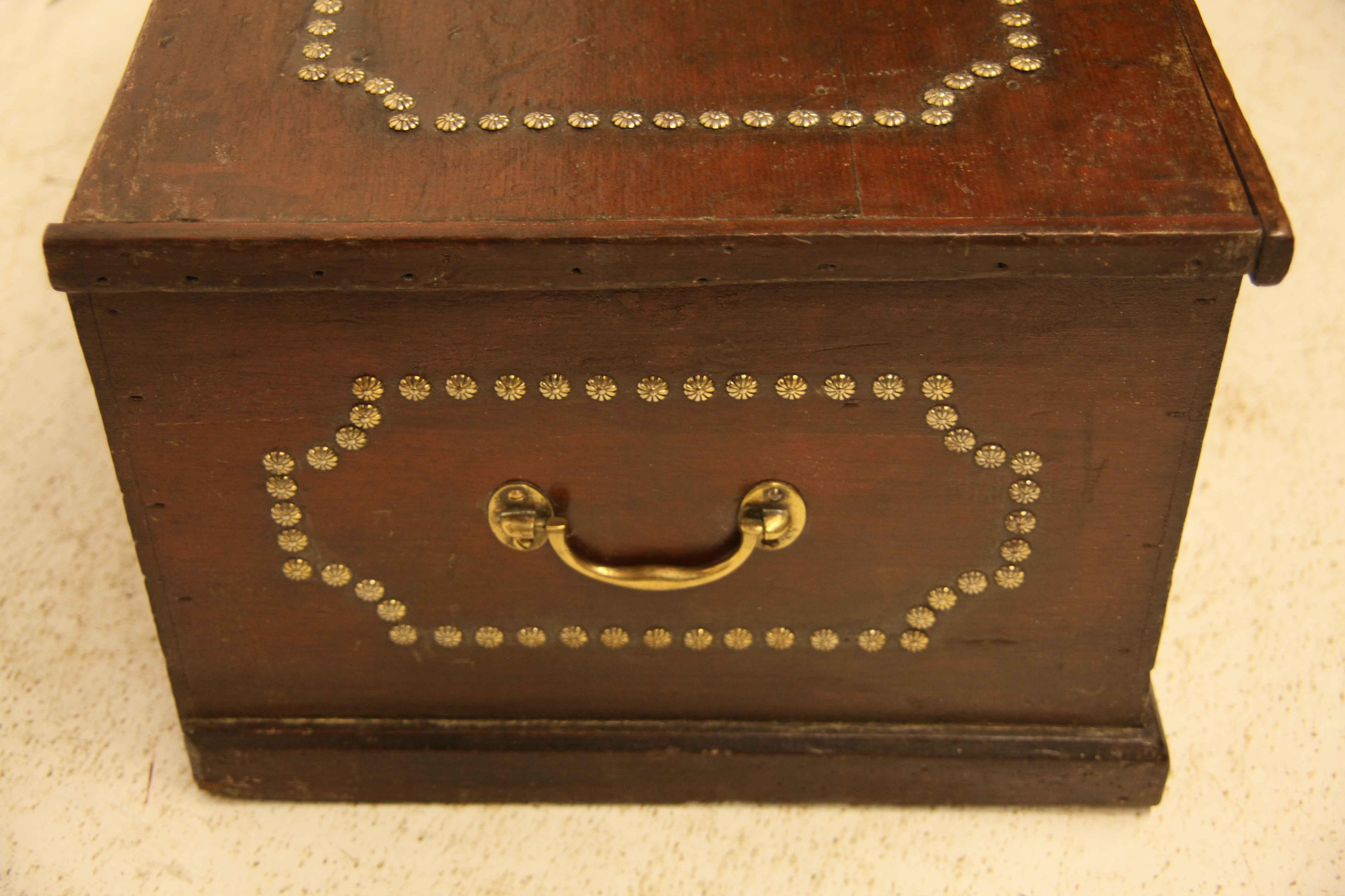 Painted pine brass studded box, the top, front, and sides are decorated with brass studs in rectangle shapes with concave corners; sides have brass carrying handles; open interior with original ''rat tail'' steel hinges.