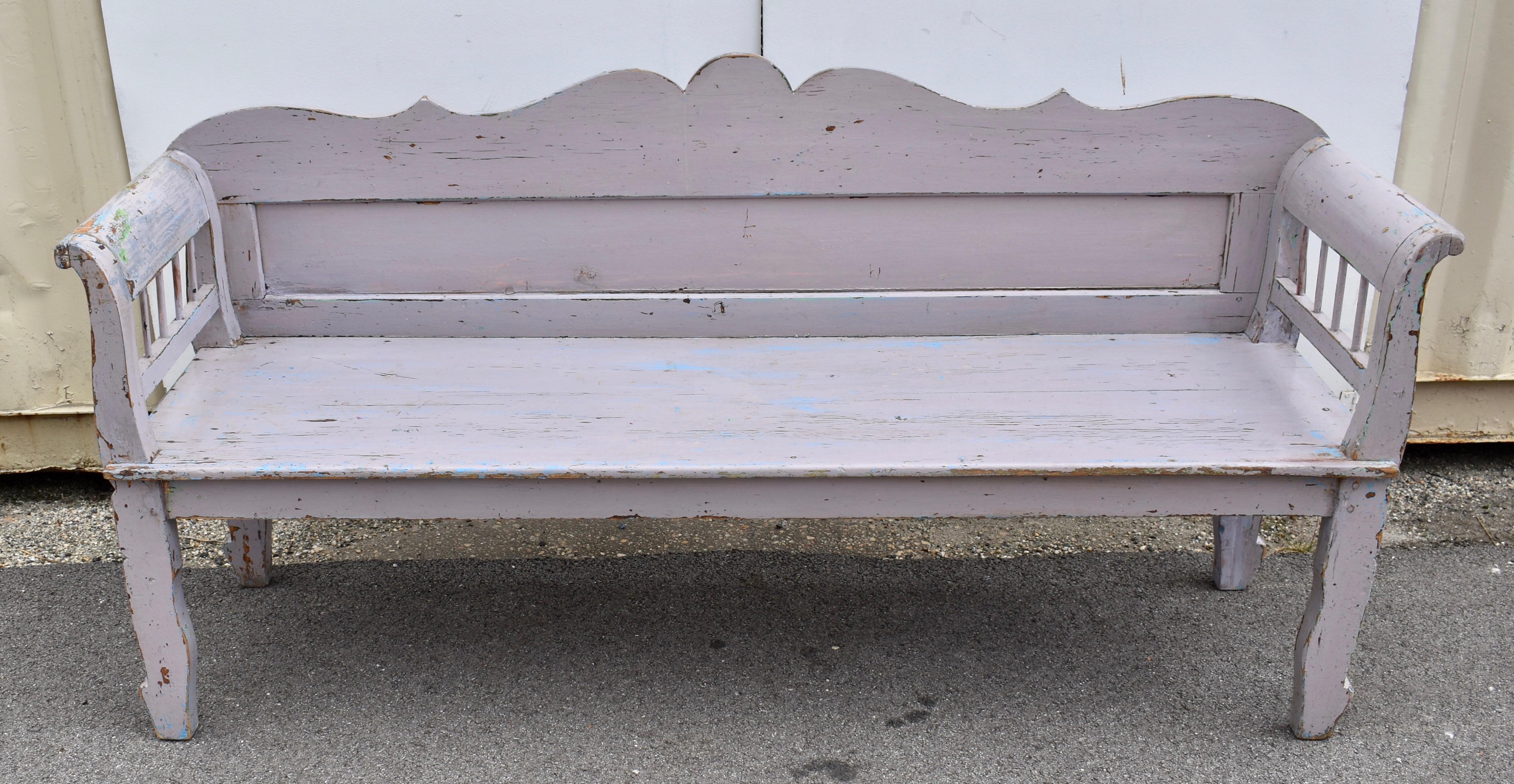 The top rail of this pretty bench is boldly scalloped and with the other backboards frames a single long rectangular panel.  The legs are notched to give a cabriole effect and end with a simplified Louis XV foot.  The integral armrests curve into an