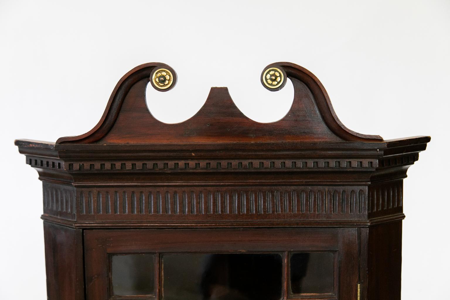 This painted pine hanging corner cupboard, to resemble mahogany, retains the original paint and has the original wavy glass panes and original working lock and key. The keyhole escutcheon is late nineteenth century, but the brass hinges are