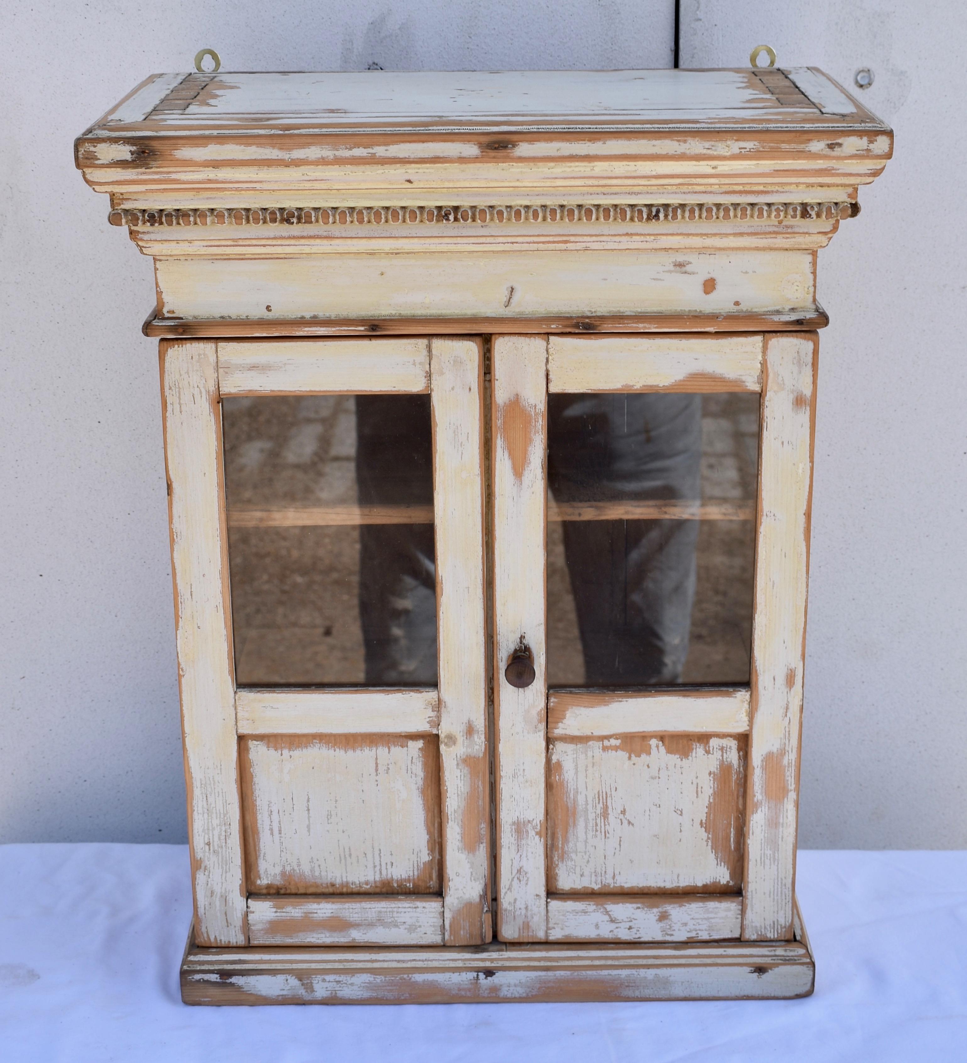 This little piece is so beautifully made that it is more a miniature armoire than a hanging cupboard. Beneath a bold crown is a tier of finely carved egg and dart molding above a plain frieze. The two doors, made with through-tenons, are half-glazed