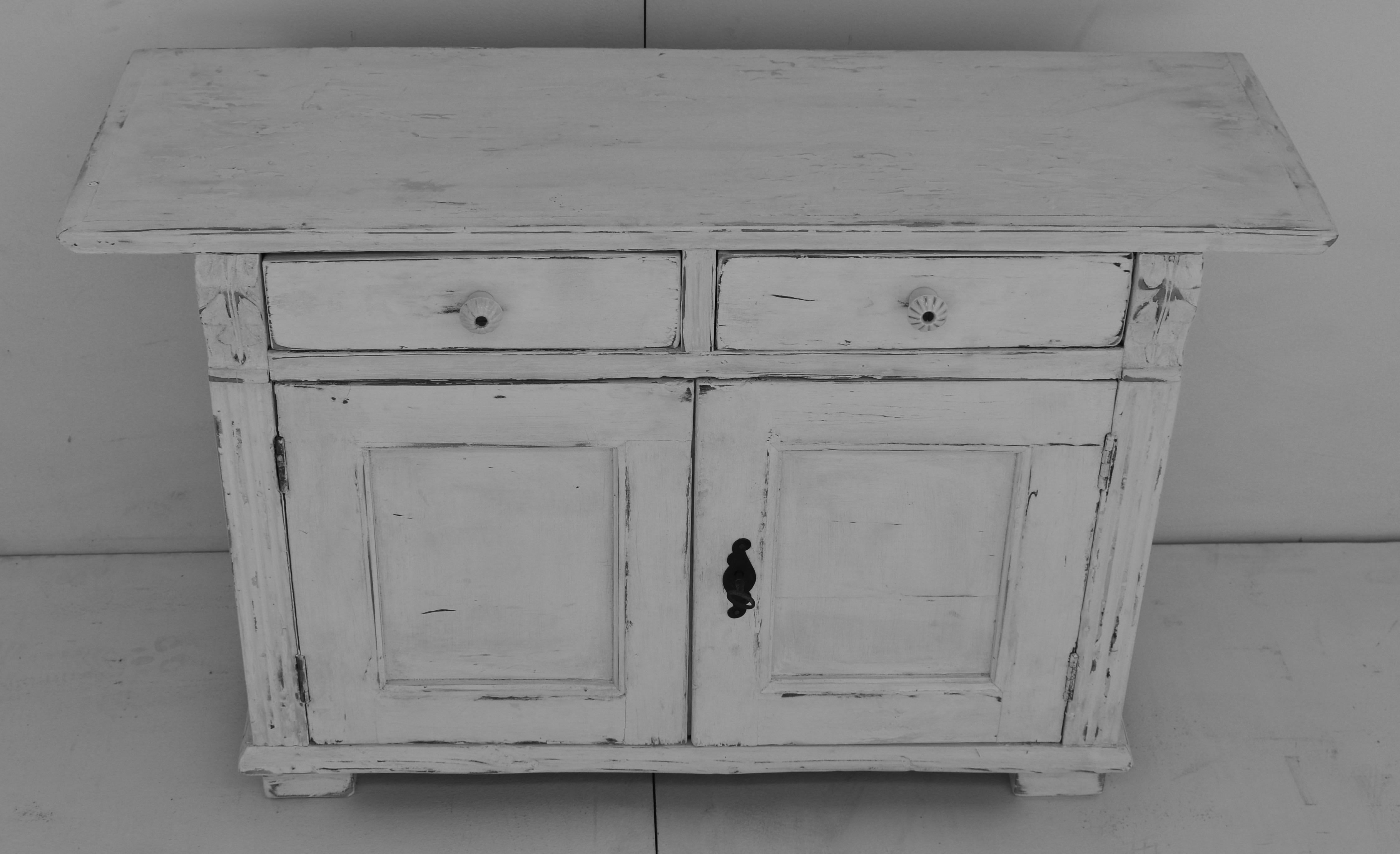 This pretty little rustic water cupboard is built low so that weighty vessels can be placed on top, and has a long overhang to maximize its utility. Its two lap-jointed drawers and two wide-swinging paneled doors are flanked by fluted molding and