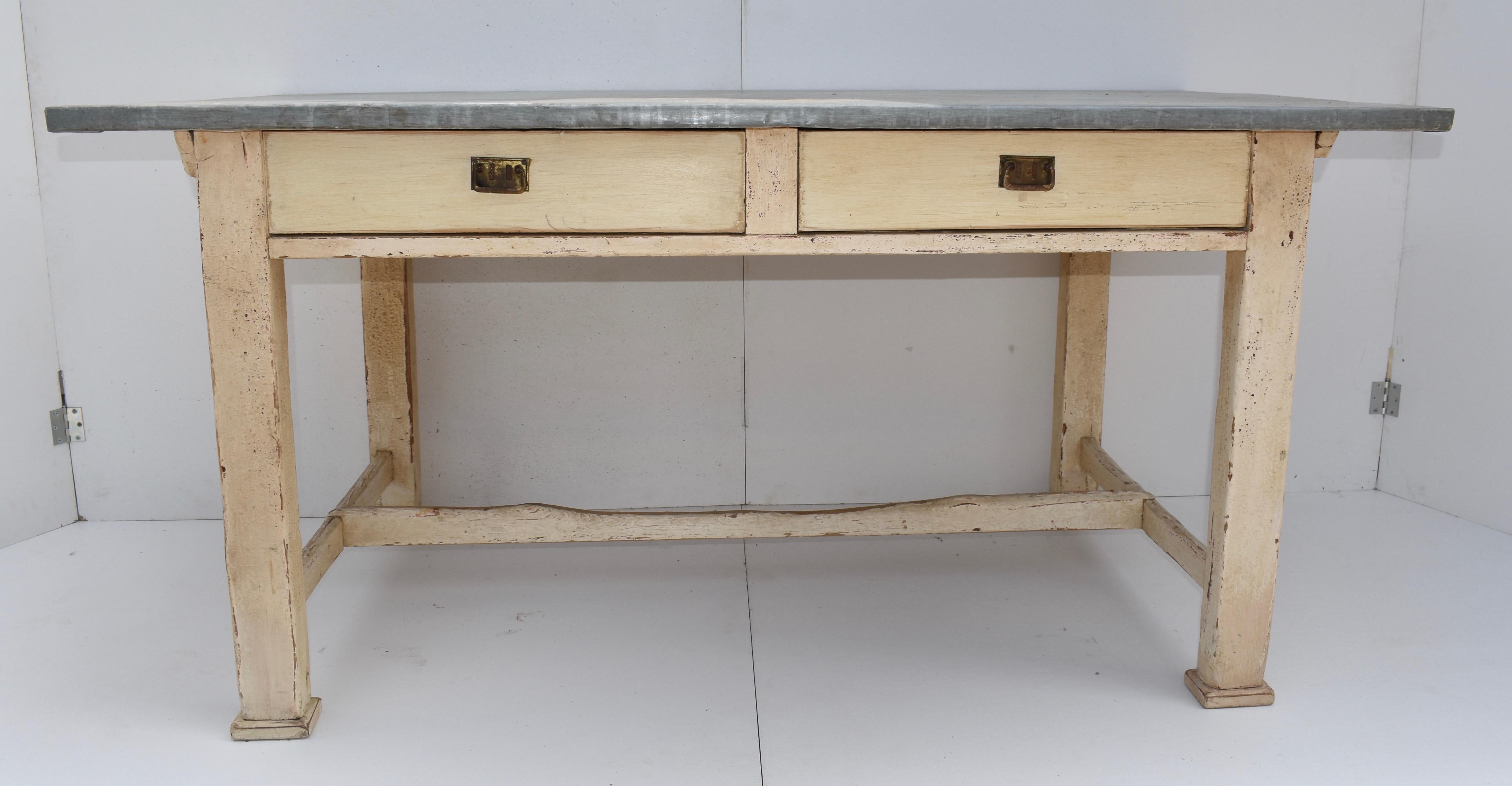 This sturdy zinc-topped work table has two large handcut dovetailed drawers with metal bail pulls and square legs joined by stretchers. Zinc-topped tables were frequently used for folding and sorting clothing and linens during laundering. From the