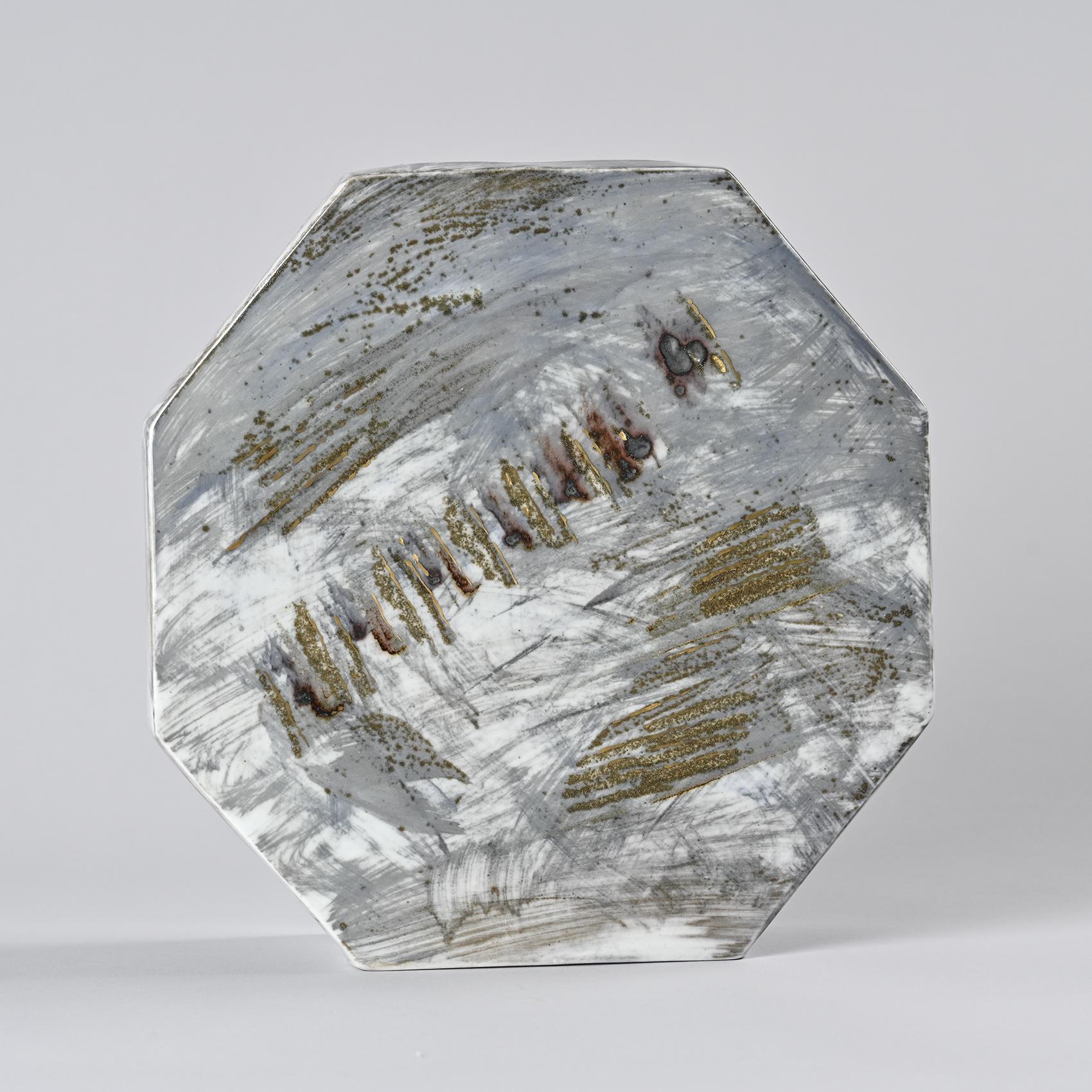 
Vase octogonal en grès émaillé dans des tons gris, bruns et or, caractéristiques des techniques de cuisson au bois de La Borne. Les effets de matière, passant du mat au brillant, révèlent une maîtrise du feu et de la glaçure, mettant en valeur le