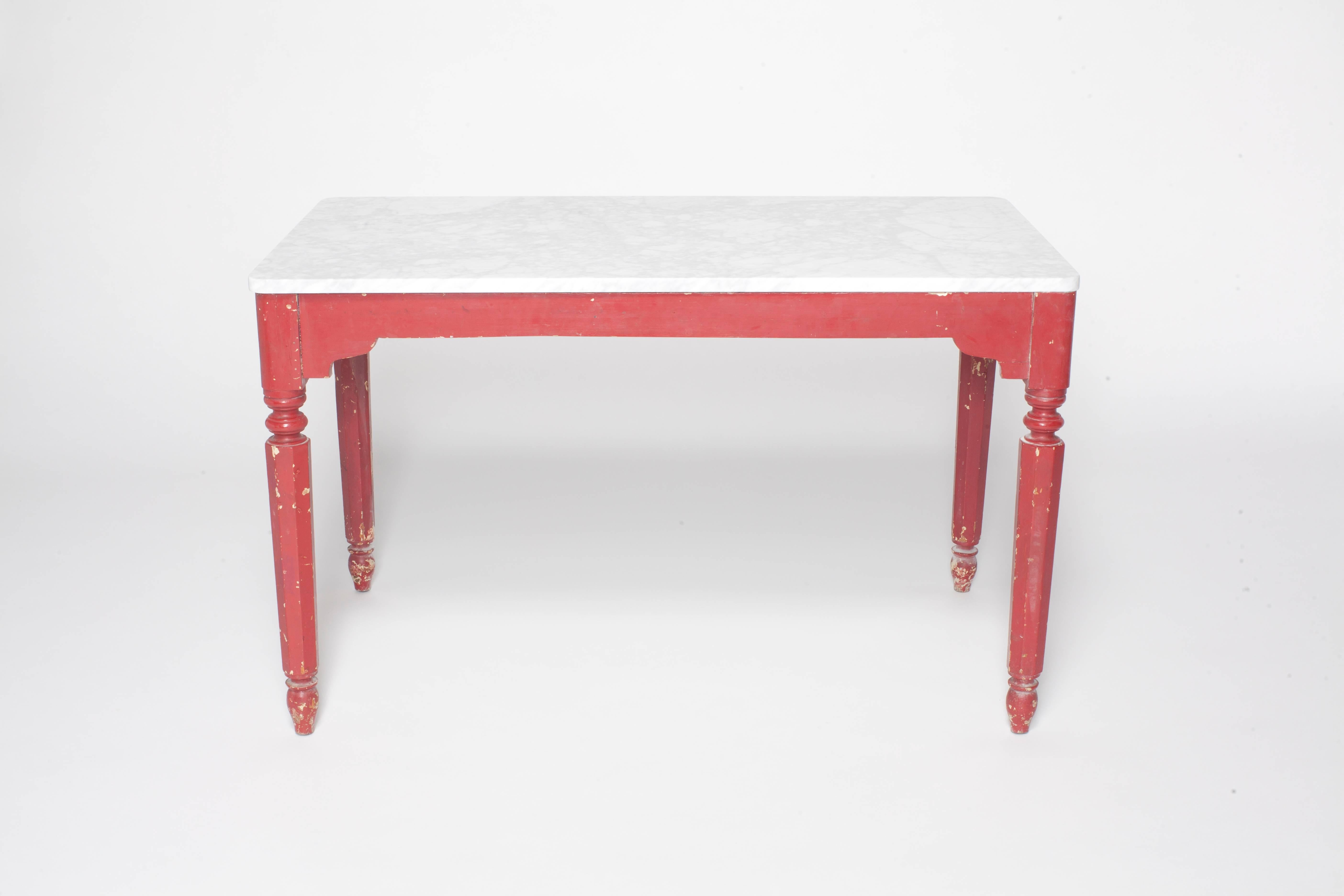 Painted red farm table with turned legs and marble top.