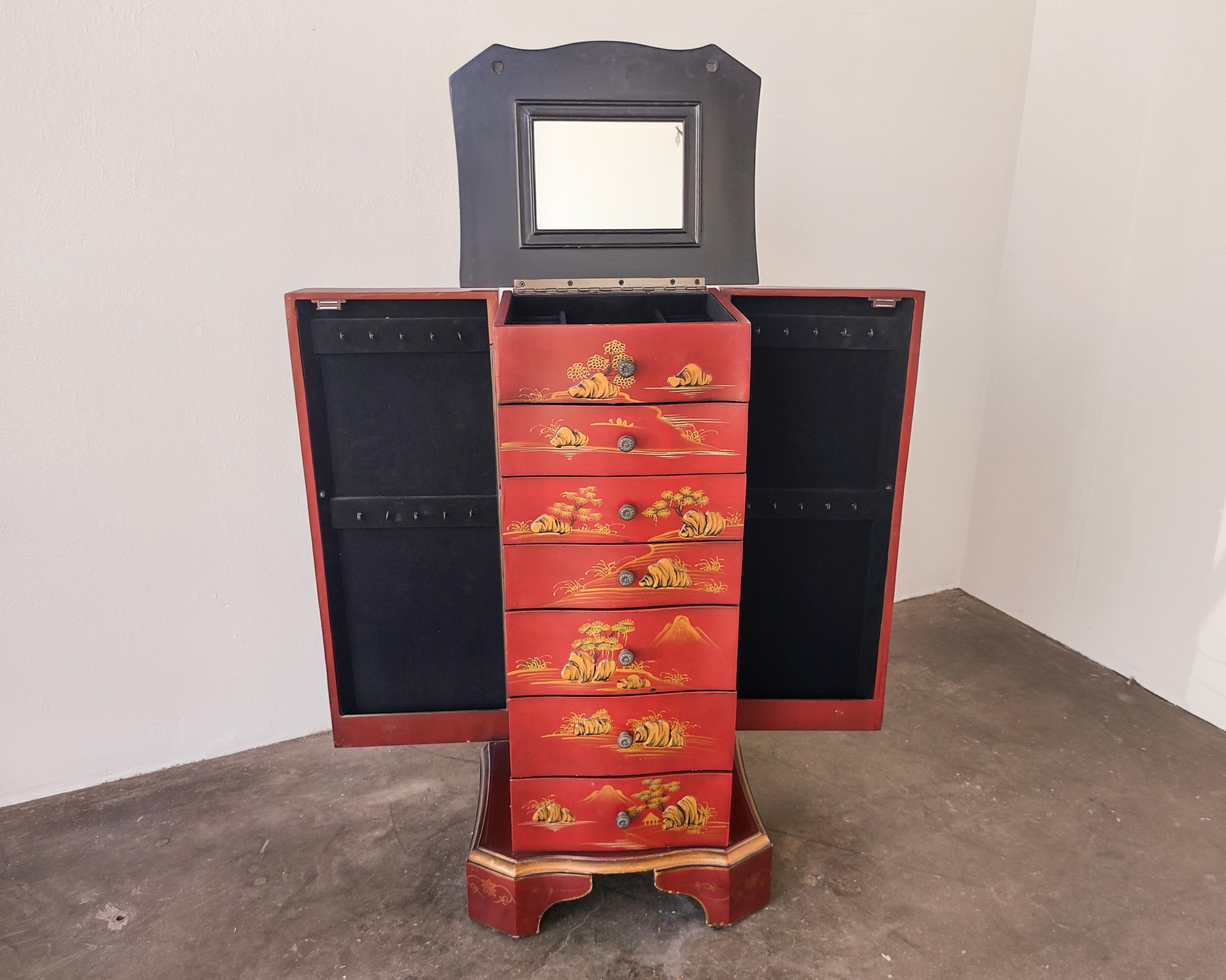Red Chinese upright jewelry chest with raised elements and beautiful gold hand painted scenes. Top opens up to vanity mirror and divided storage, six drawers down the center, each side opens up with hook storage. Overall great original condition,