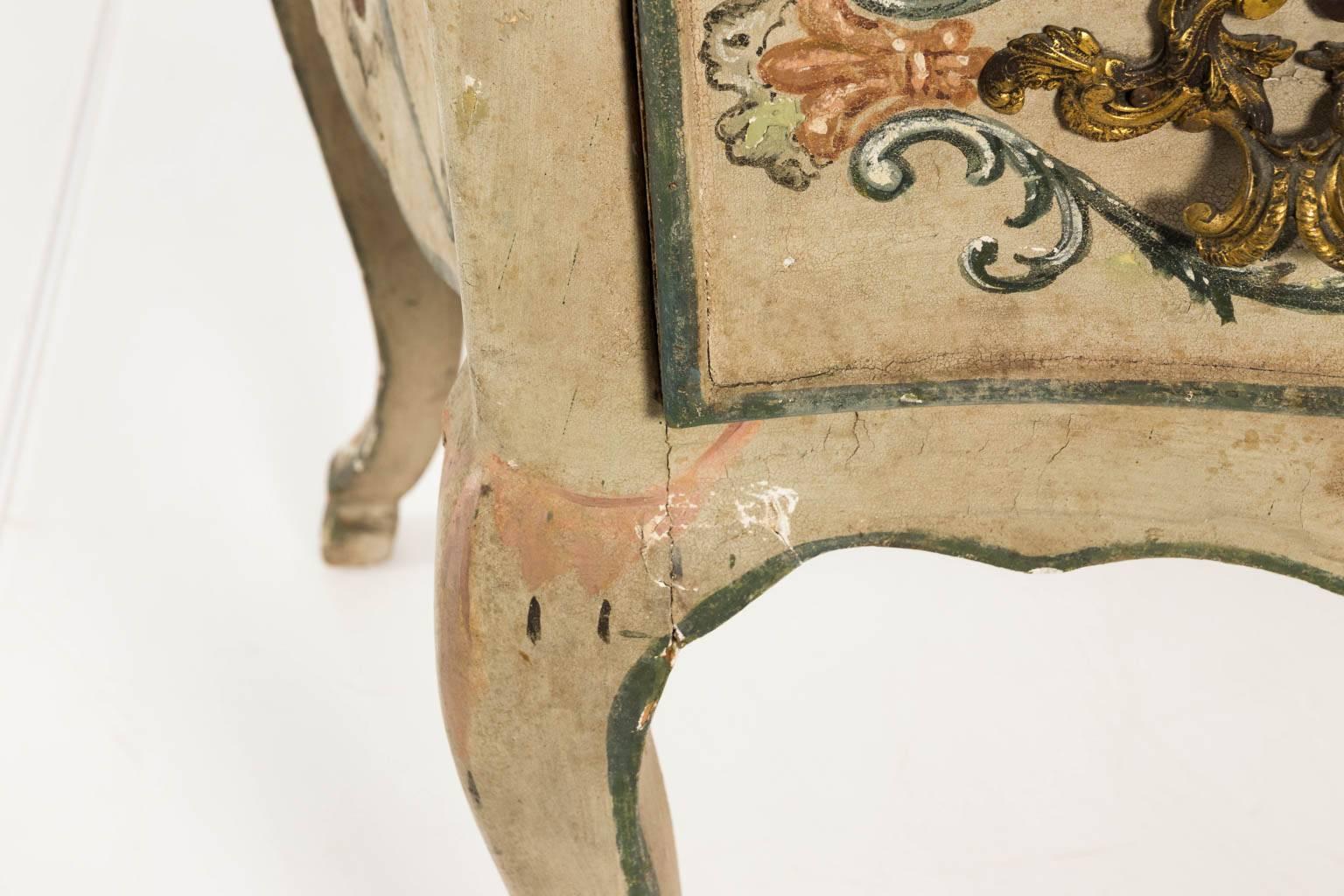 French Rococo style wooden two drawer chest of drawers that features a faux marble top, brass foliage hardware and delicately painted floral designs throughout, circa late 19th century. Minor paint loss from use.
 