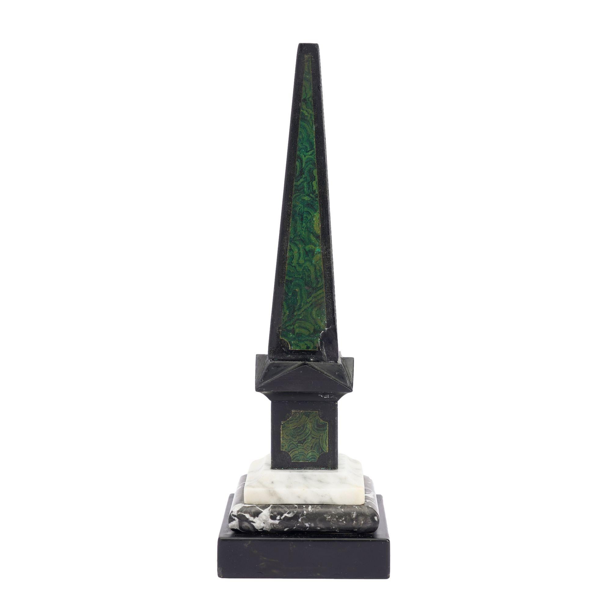 Tapered square obelisk in painted slate with faux malachite panels on three sides, rising from architectural pediments atop each side of the square plinth. The plinth is mounted on a square base of cove cut white marble over a pillow cut gray &