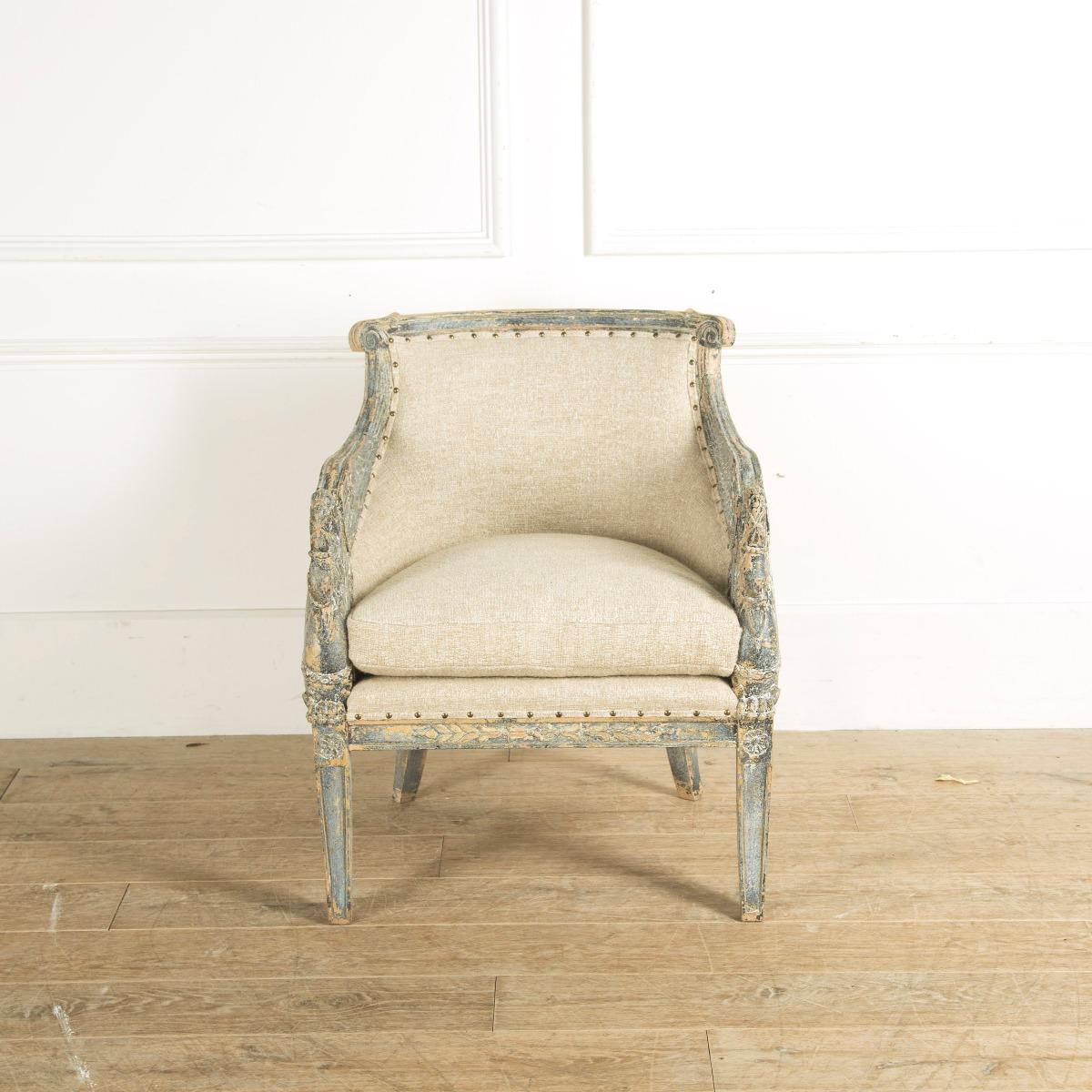 An early 20th century Empire style armchair with intricate carved swan head decoration to the armrests. Remnants of the original gilding and painted finish.