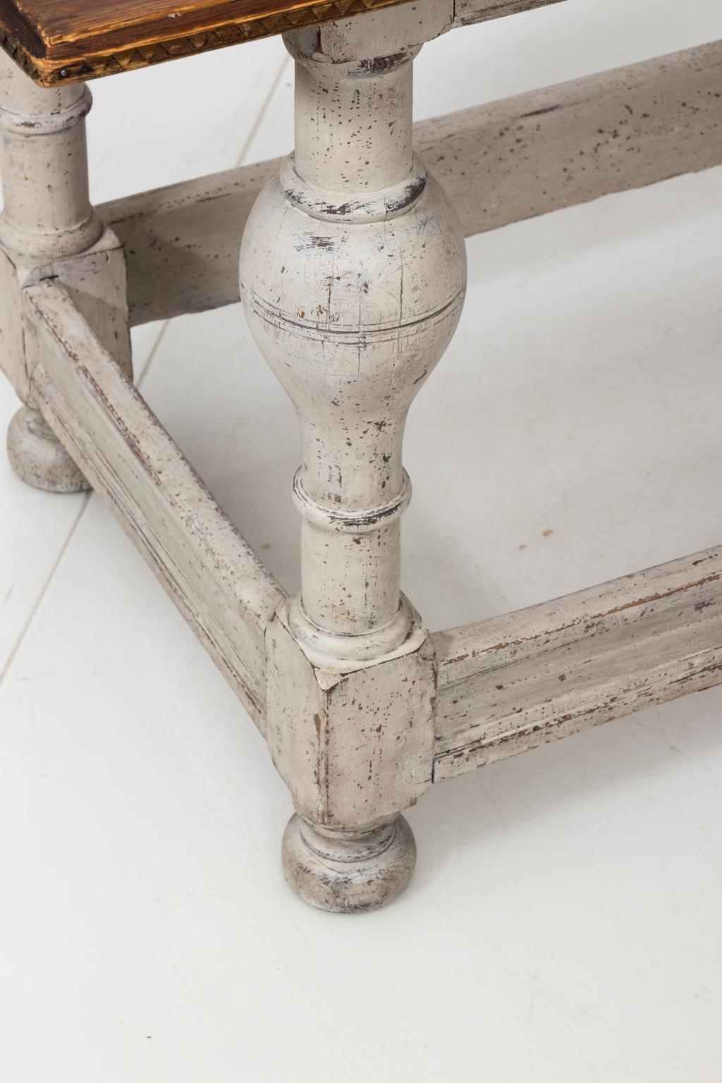 White painted pinewood table with ball turned legs and a box stretcher, circa 19th century. The table also sits on bun turned feet.
 