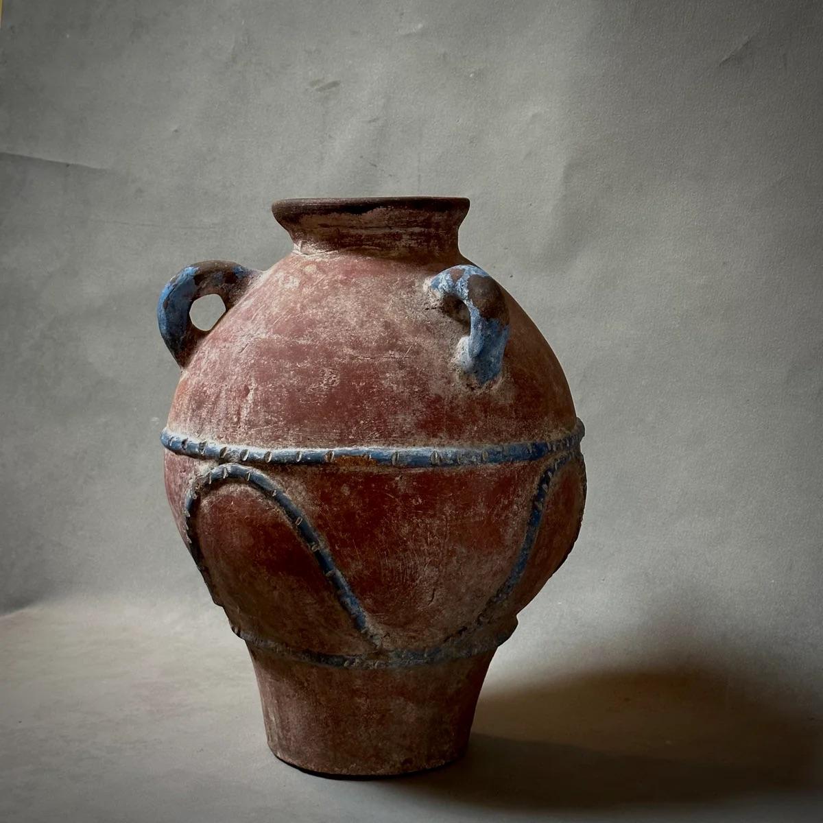 Doroteo è uno squisito vaso in terracotta dipinto a mano e impreziosito da delicati accenti blu che ne esaltano la naturale tonalità calda e rubiconda. Proveniente da uno studio di ceramisti abbandonato nella regione di Jalisco, in Messico, questo