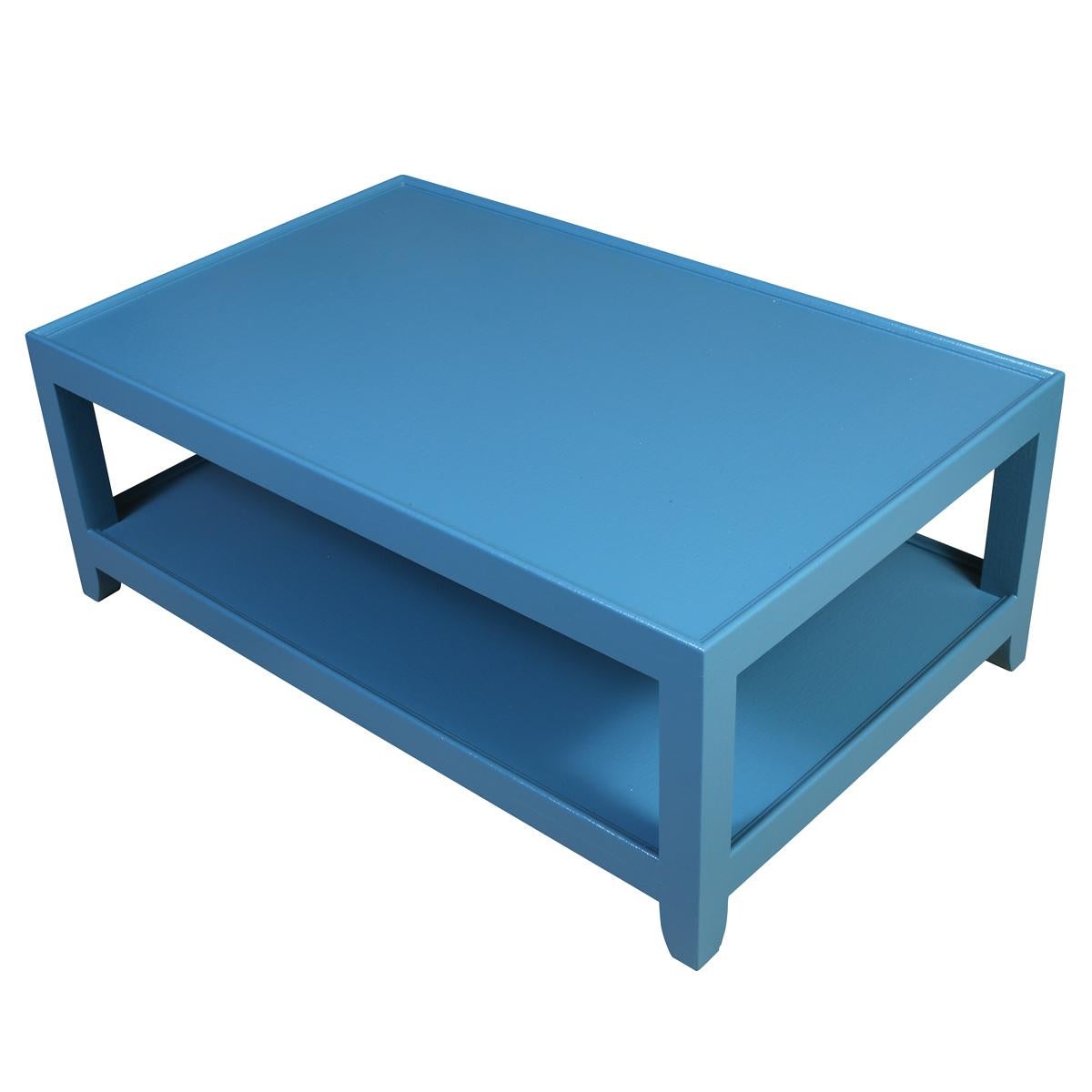 A striking two-tier coffee table, freshly painted in a vibrant blue that adds a bold pop of color to any space. The table features a clean, minimalist straight-leg silhouette and a rectilinear frame, true to classic mid-century design principles.