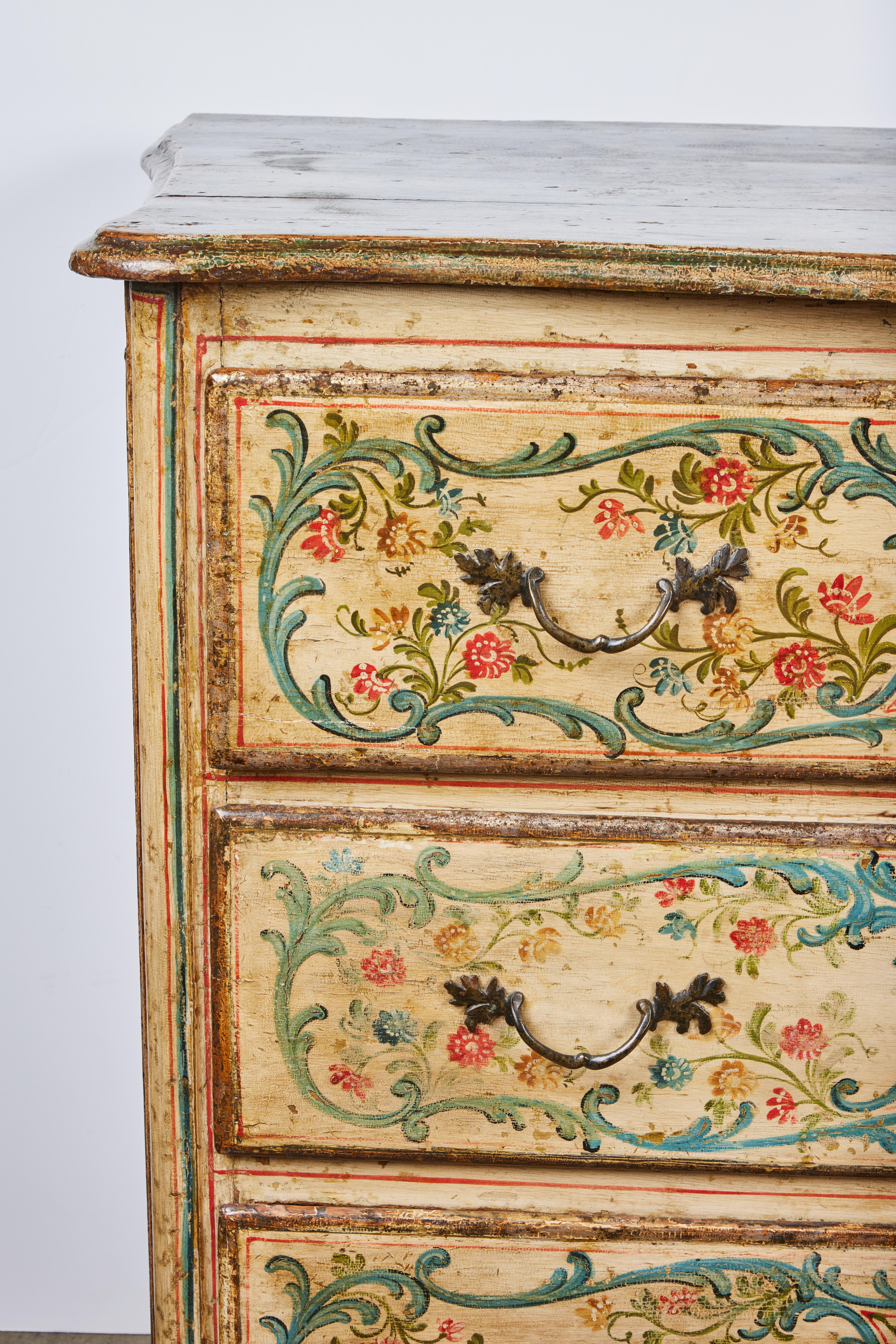 A carved and hand painted Venetian commode decorated with delicate flowers, leaves and scrolls. The inset sides fully decorated as well. 3 drawers are outlined with gilding. Faux marble painted top. Bronze hardware.  Drawers are fabric lined with
