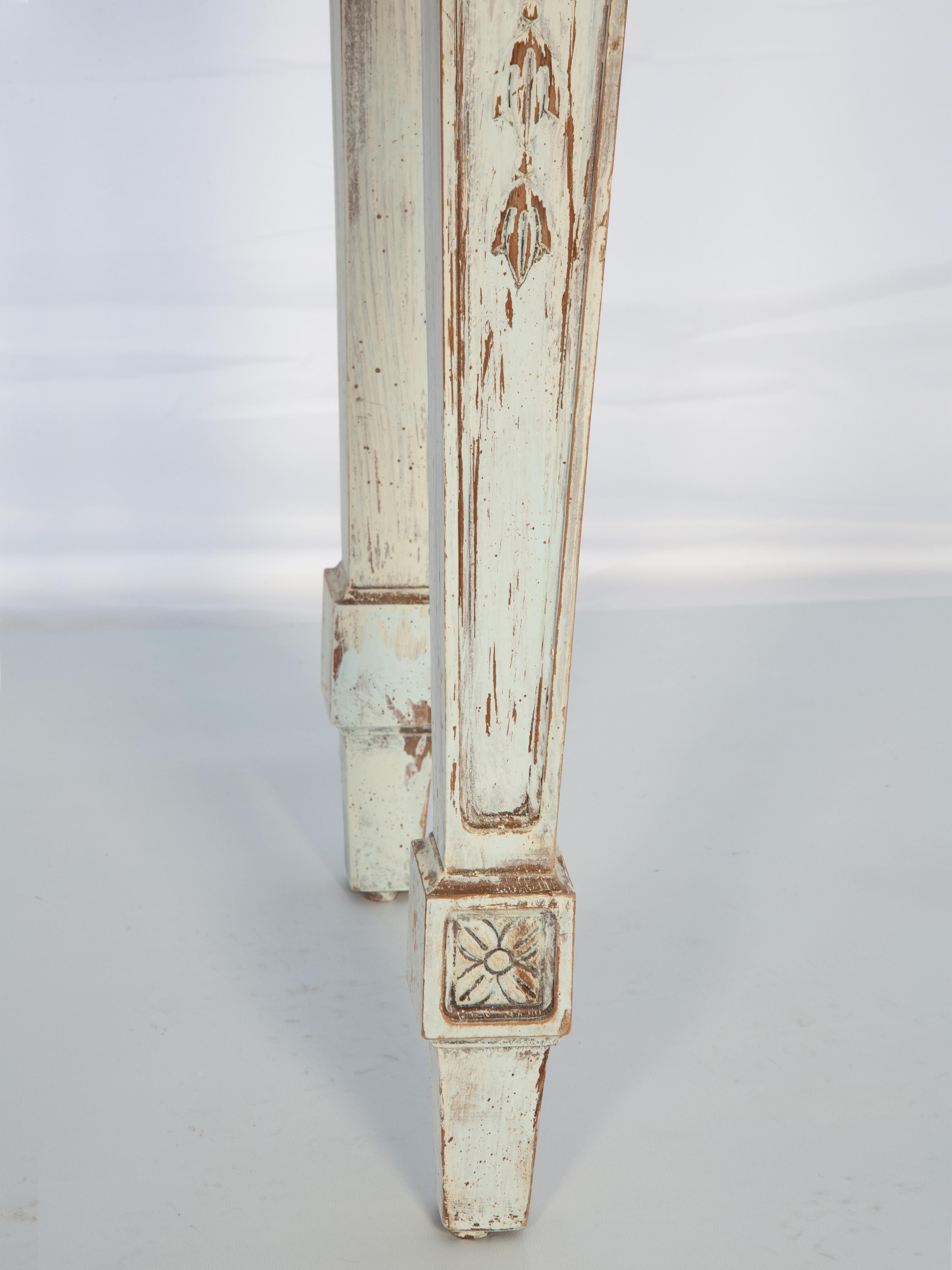 Etroite table console vintage, par Century Furniture, avec un plateau rectangulaire en marbre, sur une base peinte montrant une usure naturelle. Son tablier est centré par une coquille Saint-Jacques sculptée à la main, flanquée d'appliques en S,