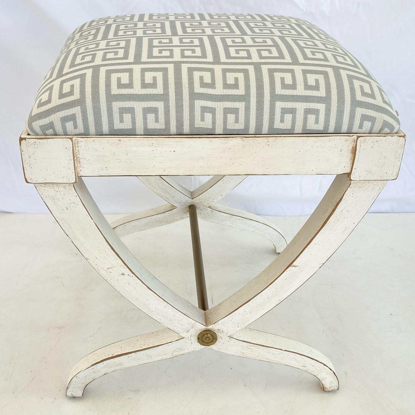 Vintage curule form stool, by Baker; having a square upholstered crown seat, on painted base. square section curving legs joined by brass pipe stretcher, legs centered by a rosette of brass.

Stock ID: D3008.