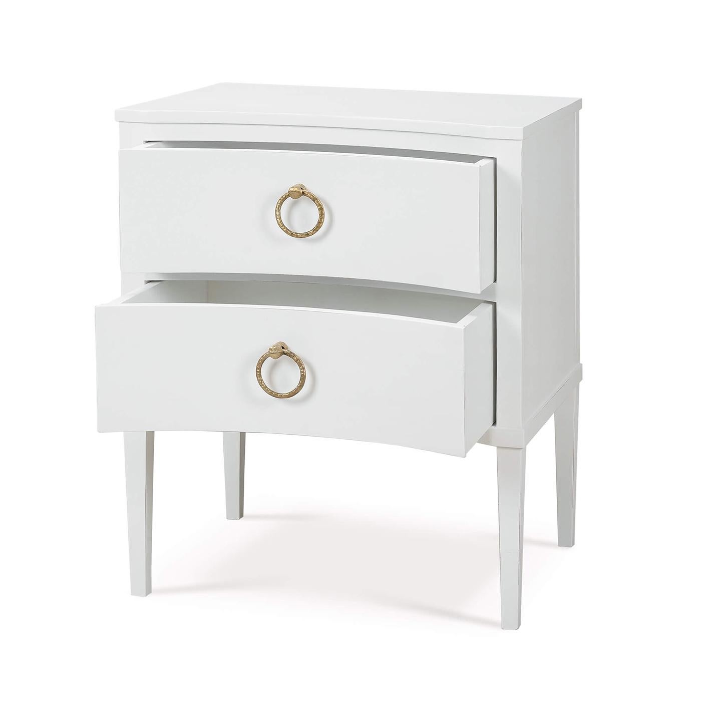 Made of mahogany and finished in a lightly distressed architectural white painted finish, this bedside table showcases the timeless beauty of classic design with a contemporary twist.

The incurved front adds a distinctive touch, while the two