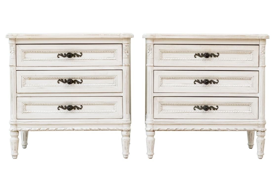 A very well made pair of Creme Painted night stands in French Cottage style. Raised on short tapered, fluted legs, with three drawers all with brass scroll form handles. Rounded front corners. The whole in white painted finish.

Dimensions: 27” wide