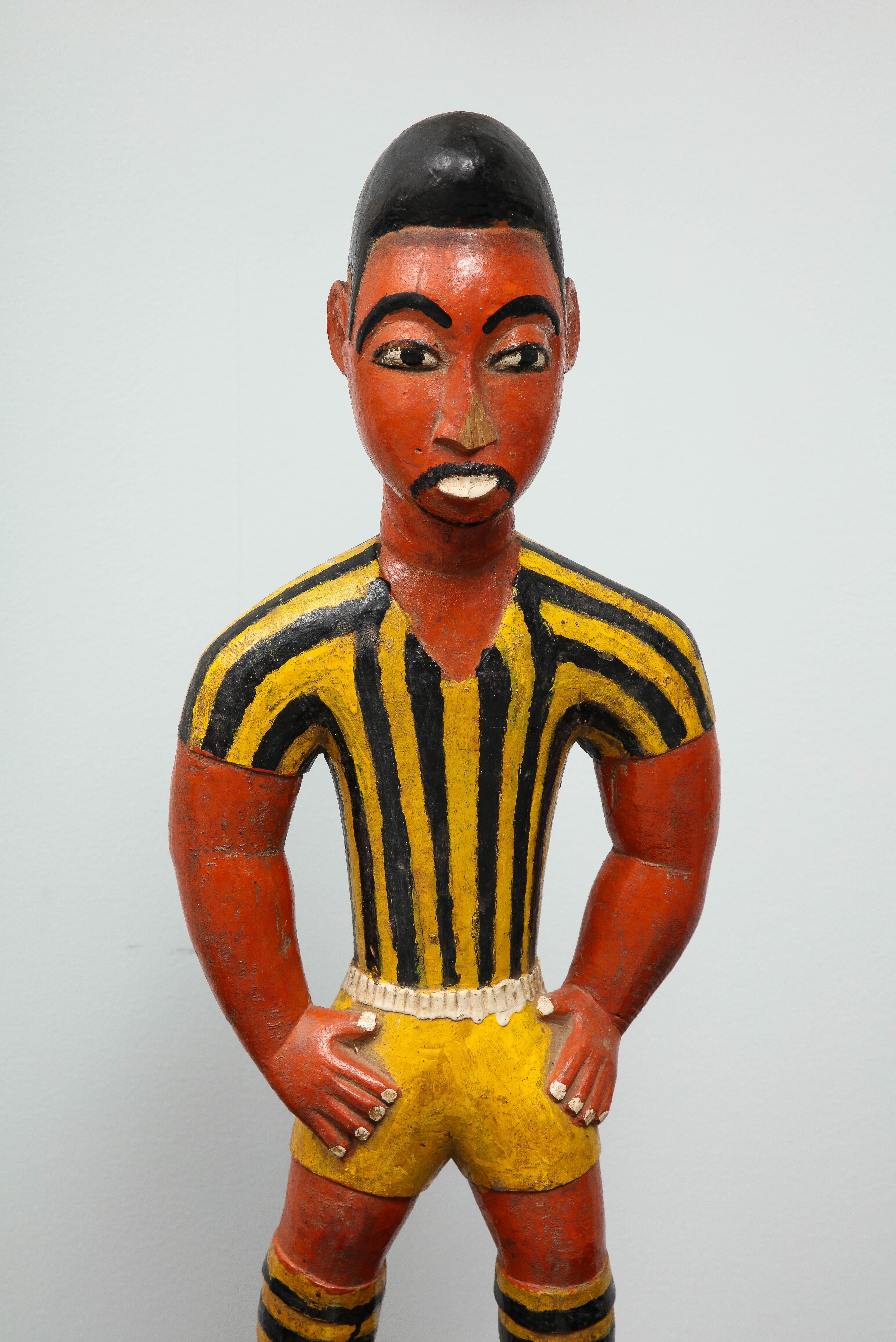 9 in football is usually worn by strikers, also known as centre-forwards. This sculpture id in wood, hand painted and shows an African football player.