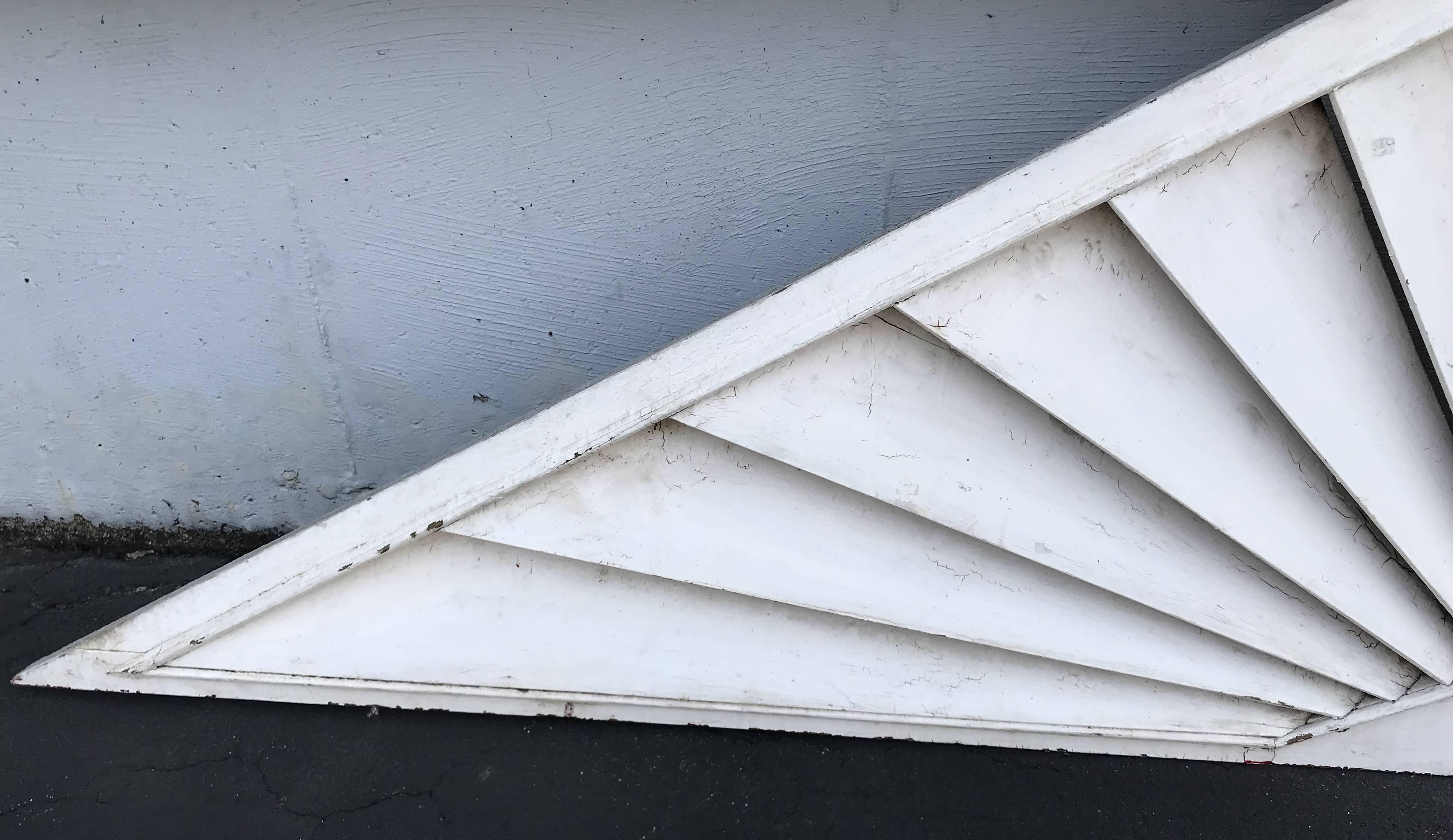 A splendid triangle form architectural transom or door fan with wooden louvers in a sunburst pattern with a molded edge surround, probably dating to the late 19th or early 20th century in white paint, with remnants of gray and red undercoats in very