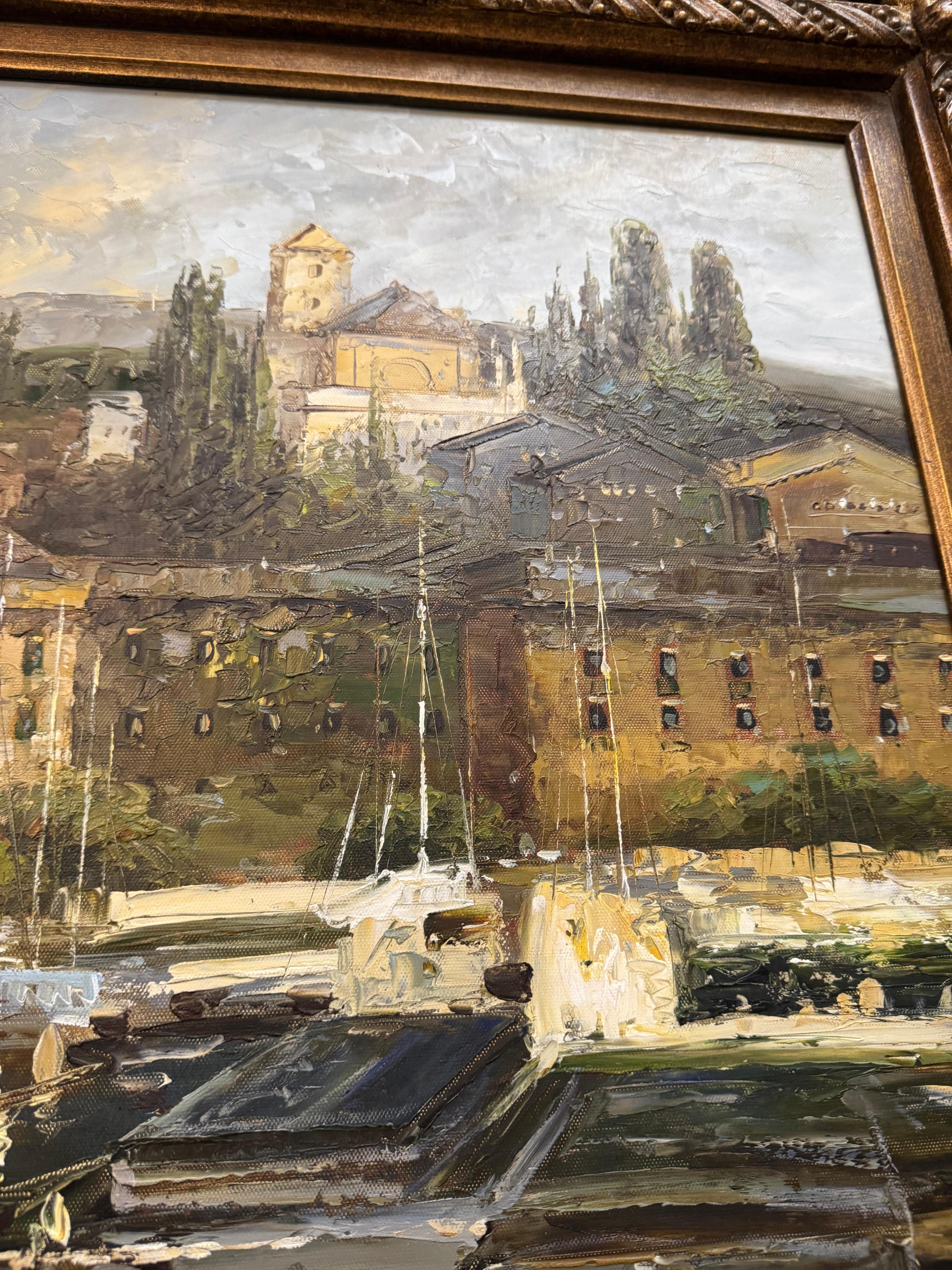 An oil painting of a harbor scene, likely European, with buildings surrounding a port filled with boats. The painting is enclosed in an ornate, gilded frame.
The style suggests it could be from the late 19th or early 20th . 
Weisner is known for