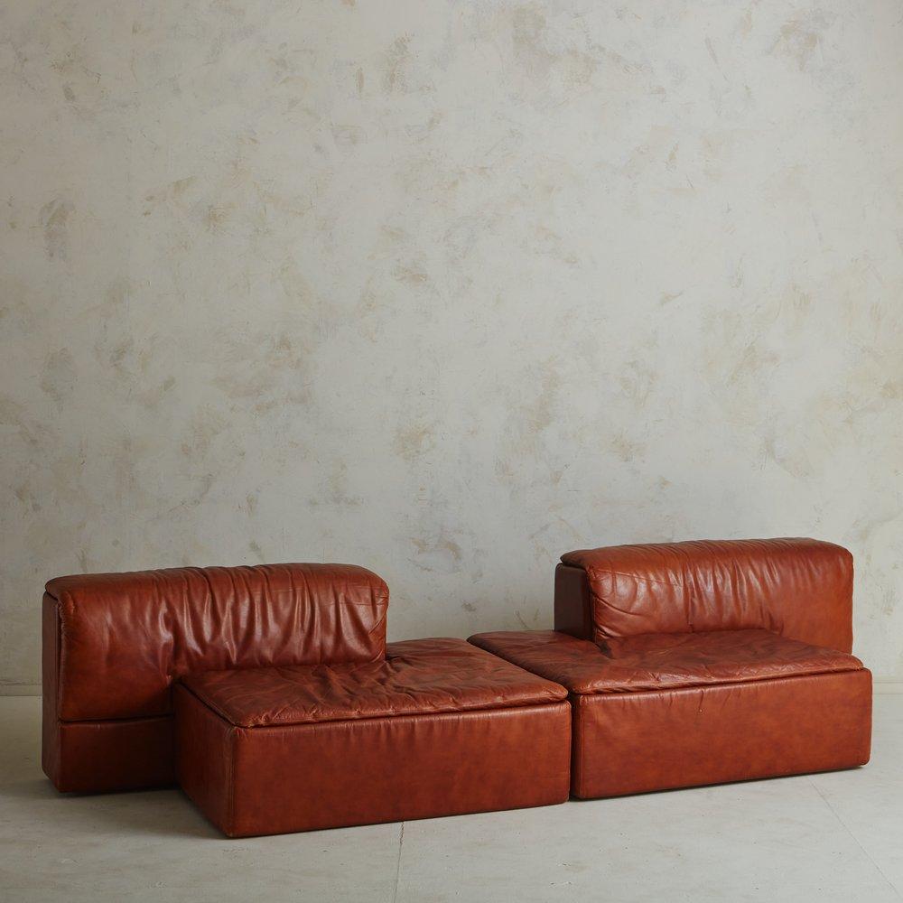 A two-piece Italian Paione sofa designed by Claudio Salocchi for Sormani in 1968. This modular sofa retains its original patinated cognac leather upholstery and can be arranged in a variety of configurations. It has integrated backrests and two