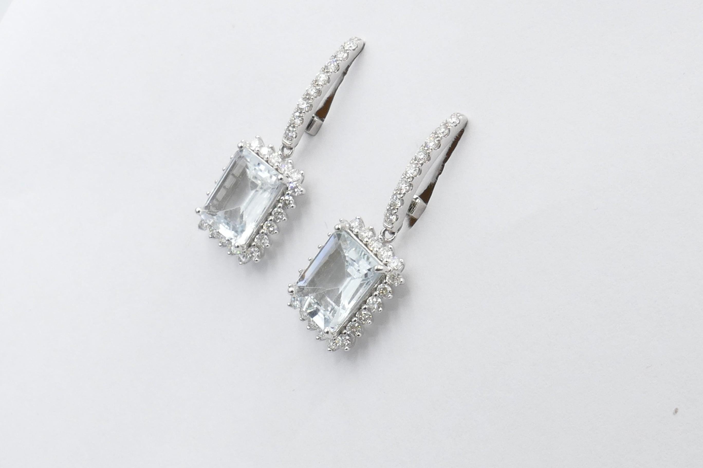 2 Aquamarine Emerald Cut Stones of 3.4+ carats, light blue in colour, eye-clean, individually 4 claw set are the Centrepiece of these very beautiful Earrings.
The Stones are surrounded by 60 Brilliant Cut Diamonds, Micro-claw set, Colour H-J,