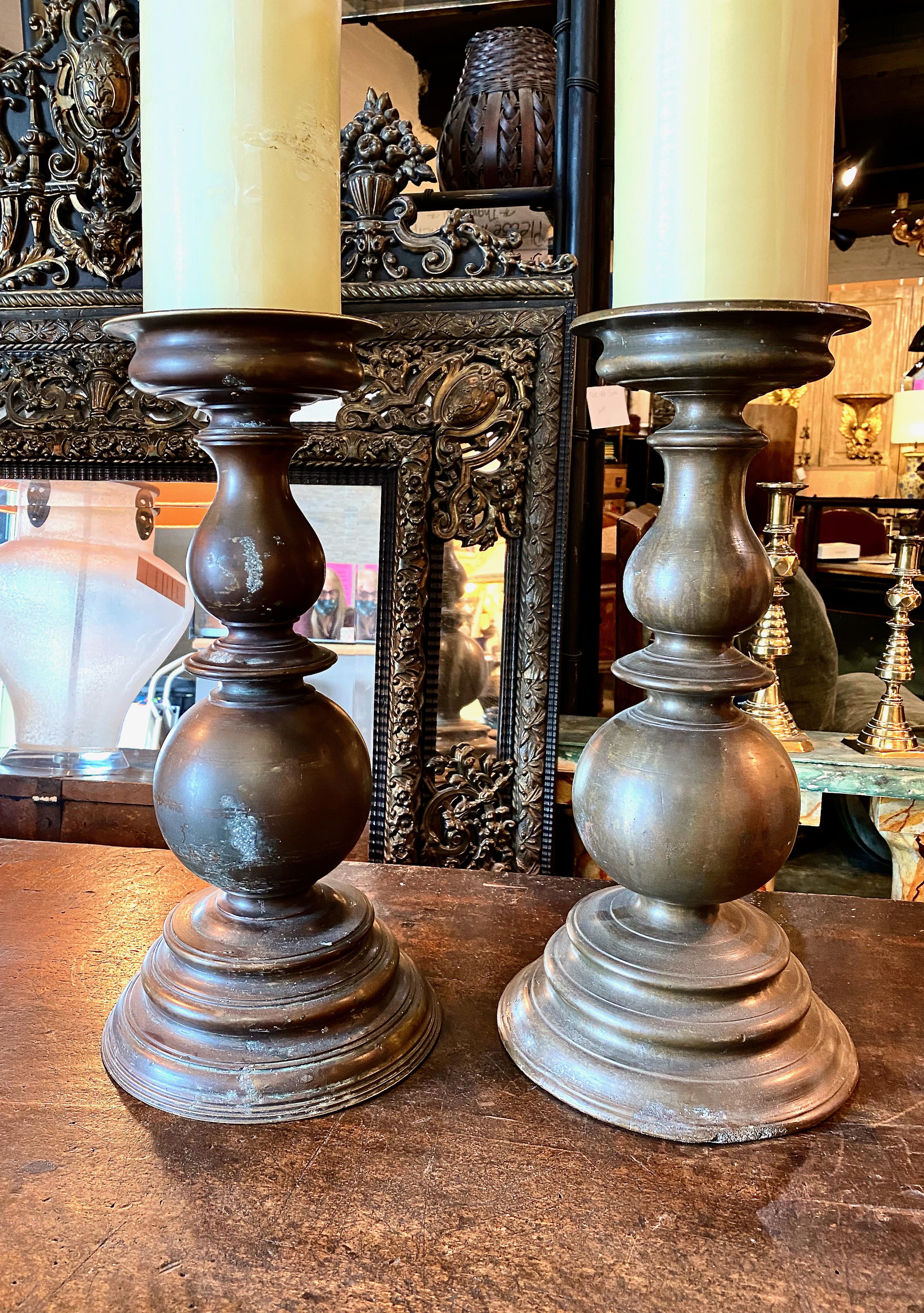This is a classic pair of fine late 17th century Italian cast bronze pricket sticks, This large pair features a rich natural patina, boldly cast turning and stepped cast base. Over their nearly 350 years of use, the candlesticks exhibit normal