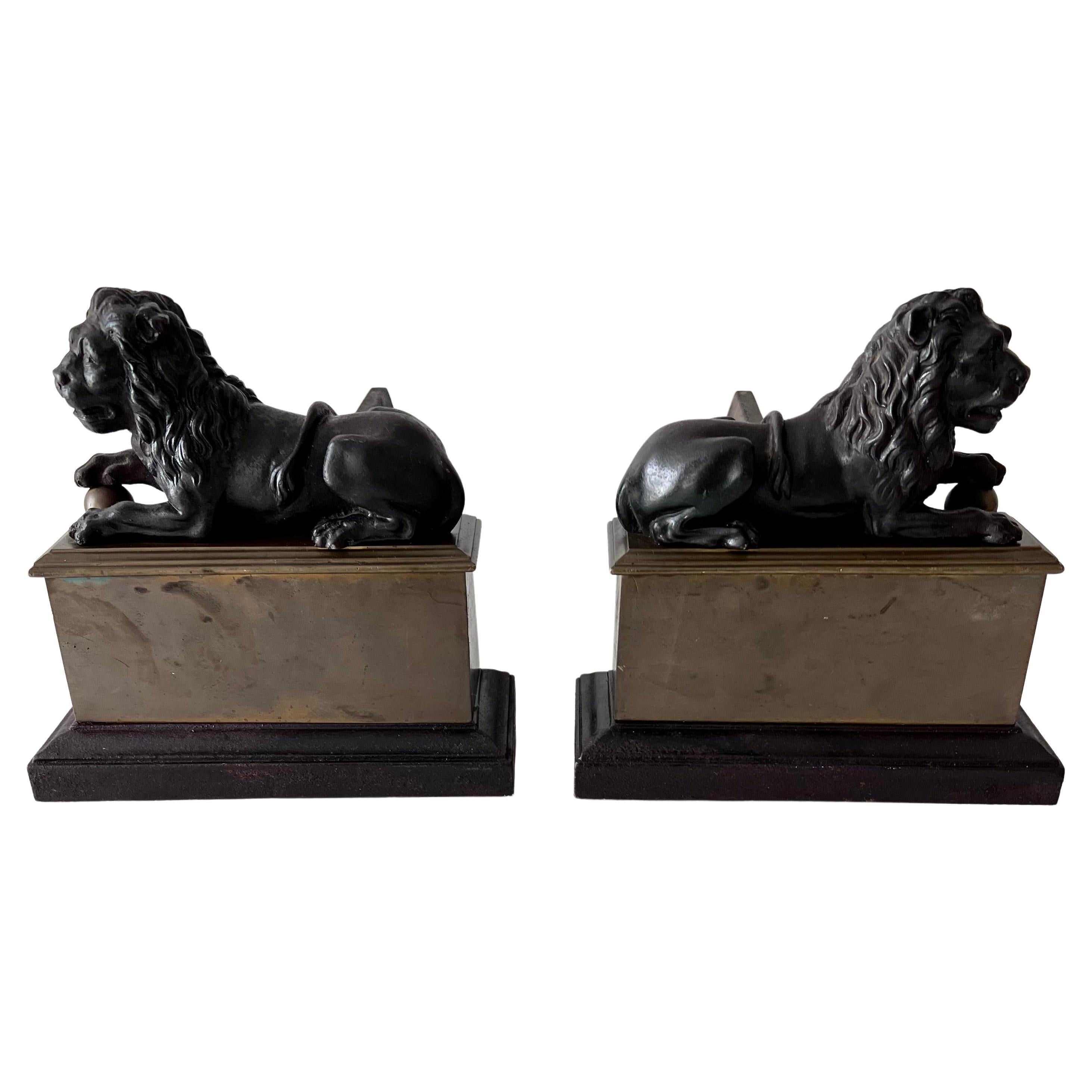 A spectacular pair of reclining wrought iron lions atop a square brass base with wrought Iron billets. The pair are rare, as we have not seen lions reclining. The look is very traditional French, however works in many spaces... the lions are nicely