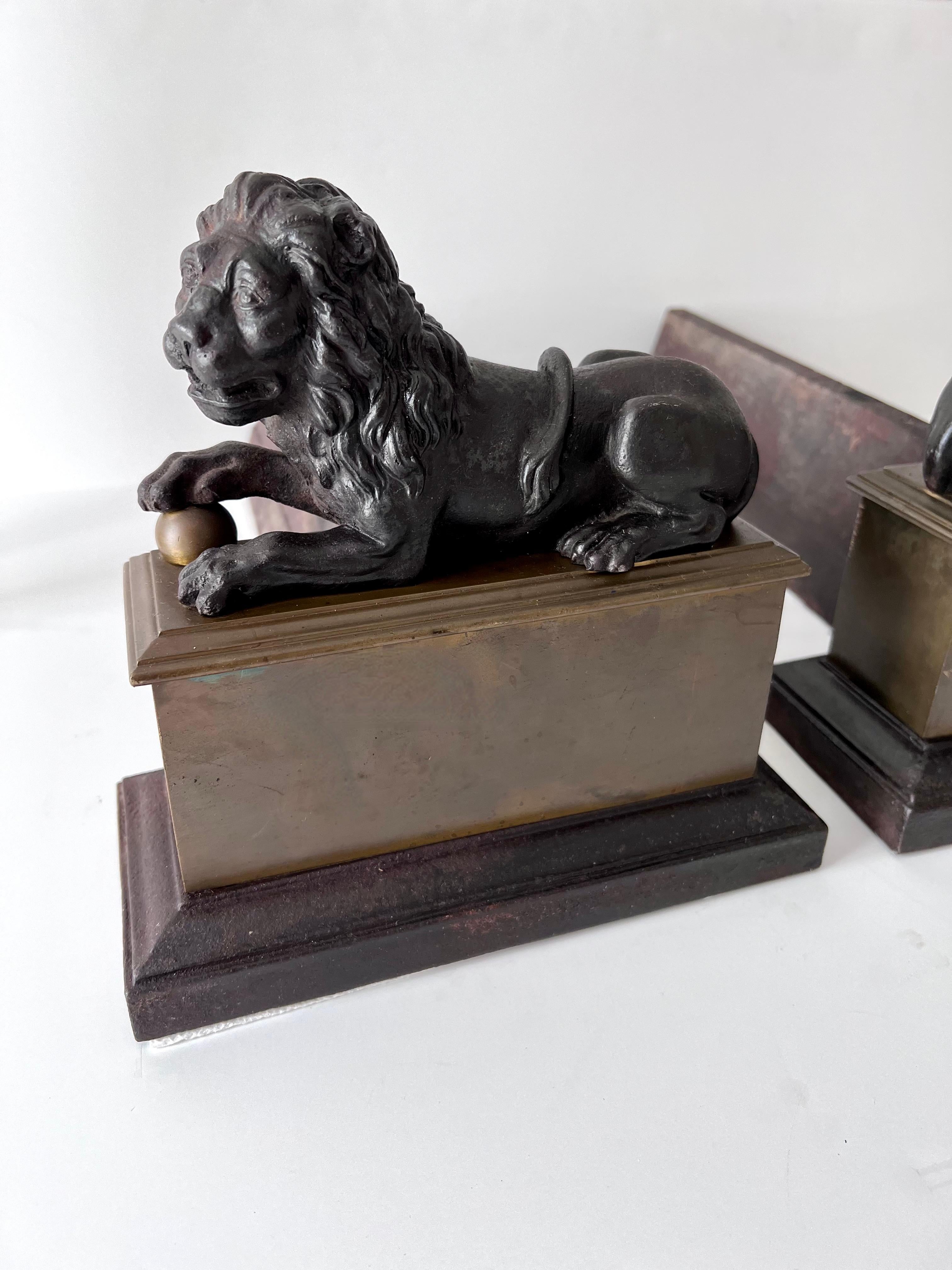 Patinated Pair 18th Century Reclining Iron Lion Andirons on a Brass Base For Sale