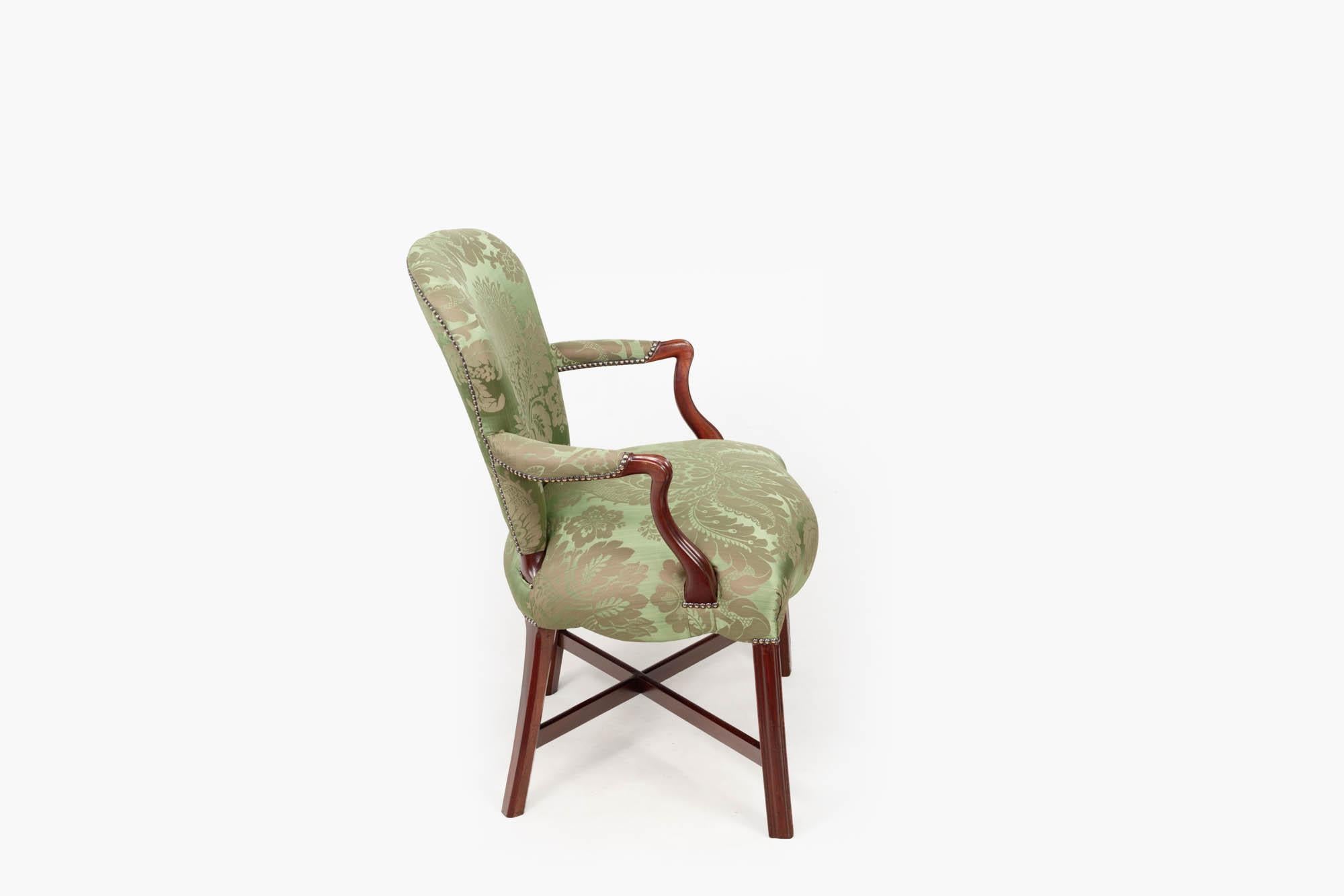 Paire de fauteuils anglais Hepplewhite du XVIIIe siècle, avec une fine tapisserie en damas vert clouté. La paire présente des sièges avant en forme de serpentin terminés par de simples pieds cannelés soutenus par des brancards en forme de X