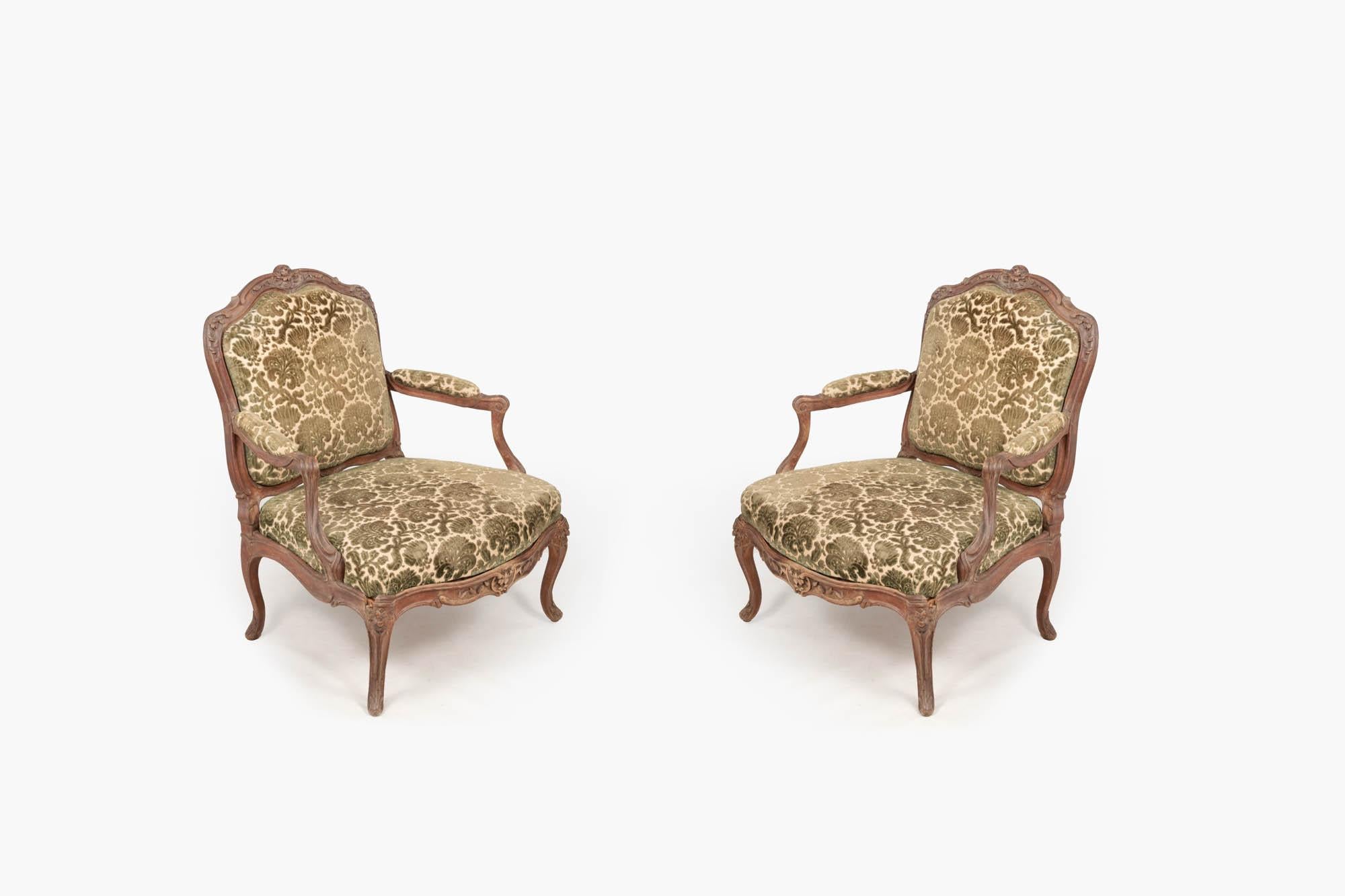 Pair 18th century French fauteuils in Louis XV style with cut velvet upholstery in fawn and green. The cartouche-shaped padded back, arms, and serpentine-fronted seats, with central floral motif on hipped cabriole legs.

This type of chair is
