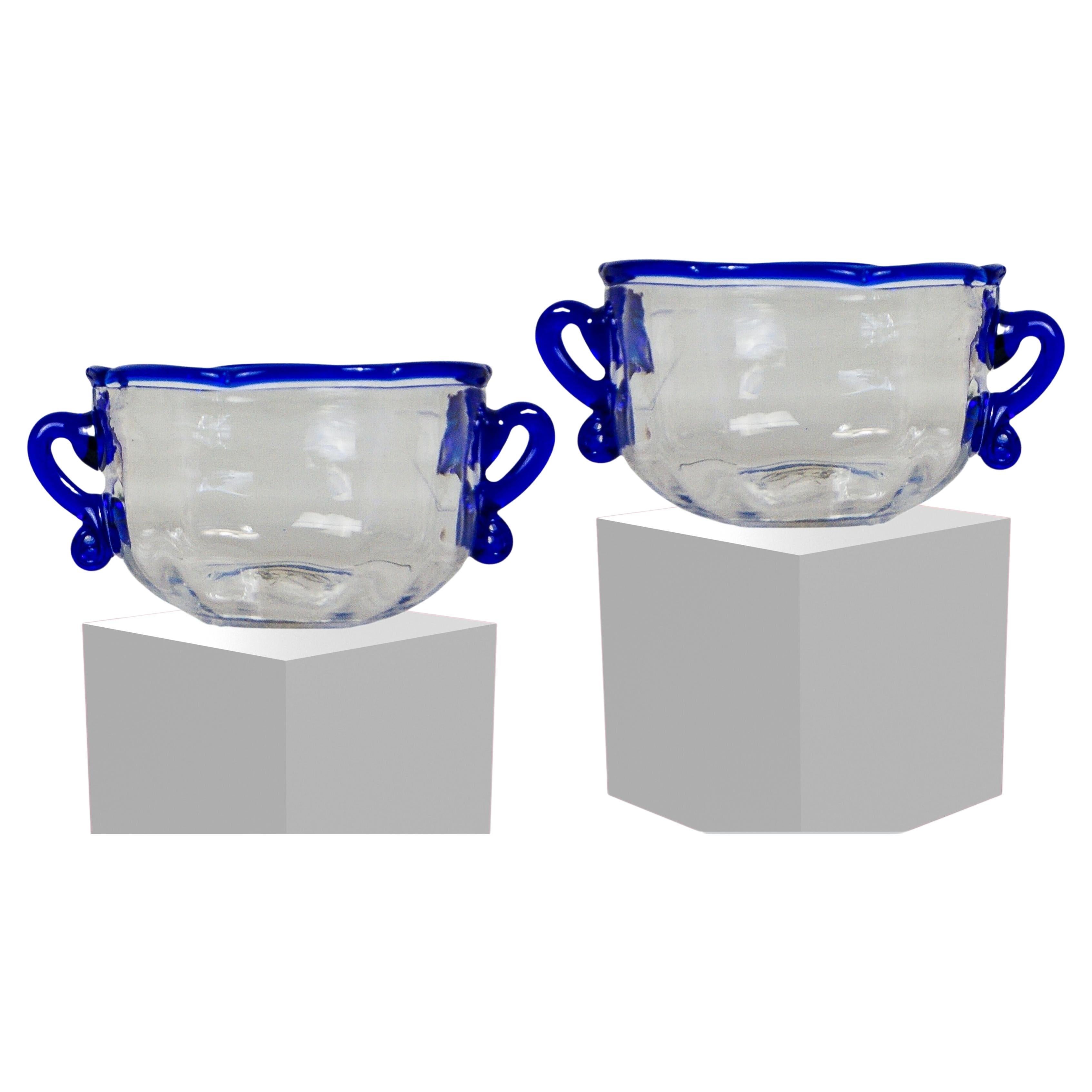 Ensemble de 2 bols en verre Wrythen de style britannique géorgien.
Datant de la fin du XVIIIe siècle et du début du XIXe siècle, vers 1800.
Verre transparent texturé et nervuré, avec bord bleu appliqué et doubles poignées bleues.
De taille