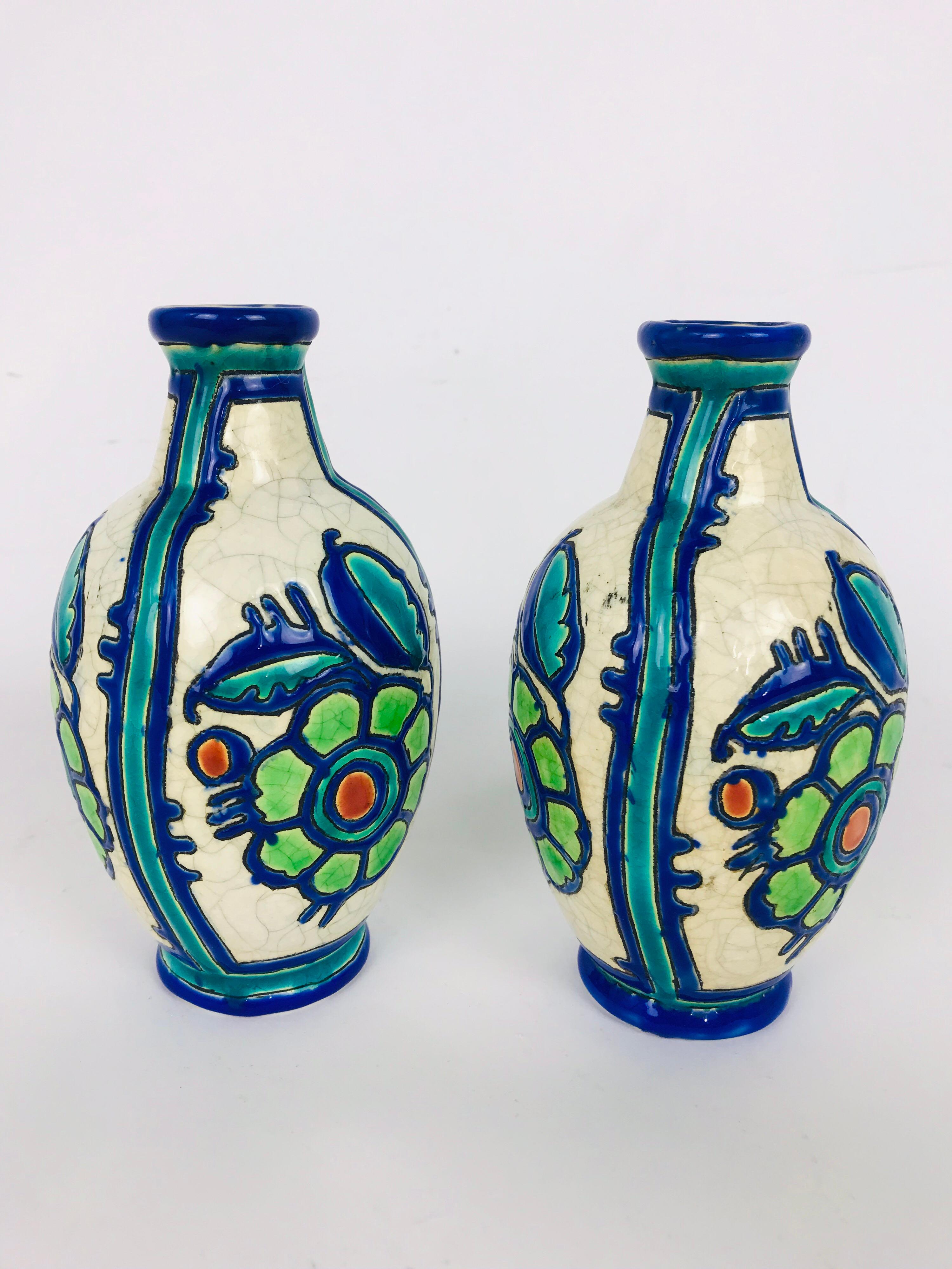 Beautiful pair of 1920s Boch Freres vases in remarkable excellent condition. All over white crackle glaze and decorated in slightly raised bright blue and green flowers with a touch of red. Each signed on the bottom under the glaze. No cracks,