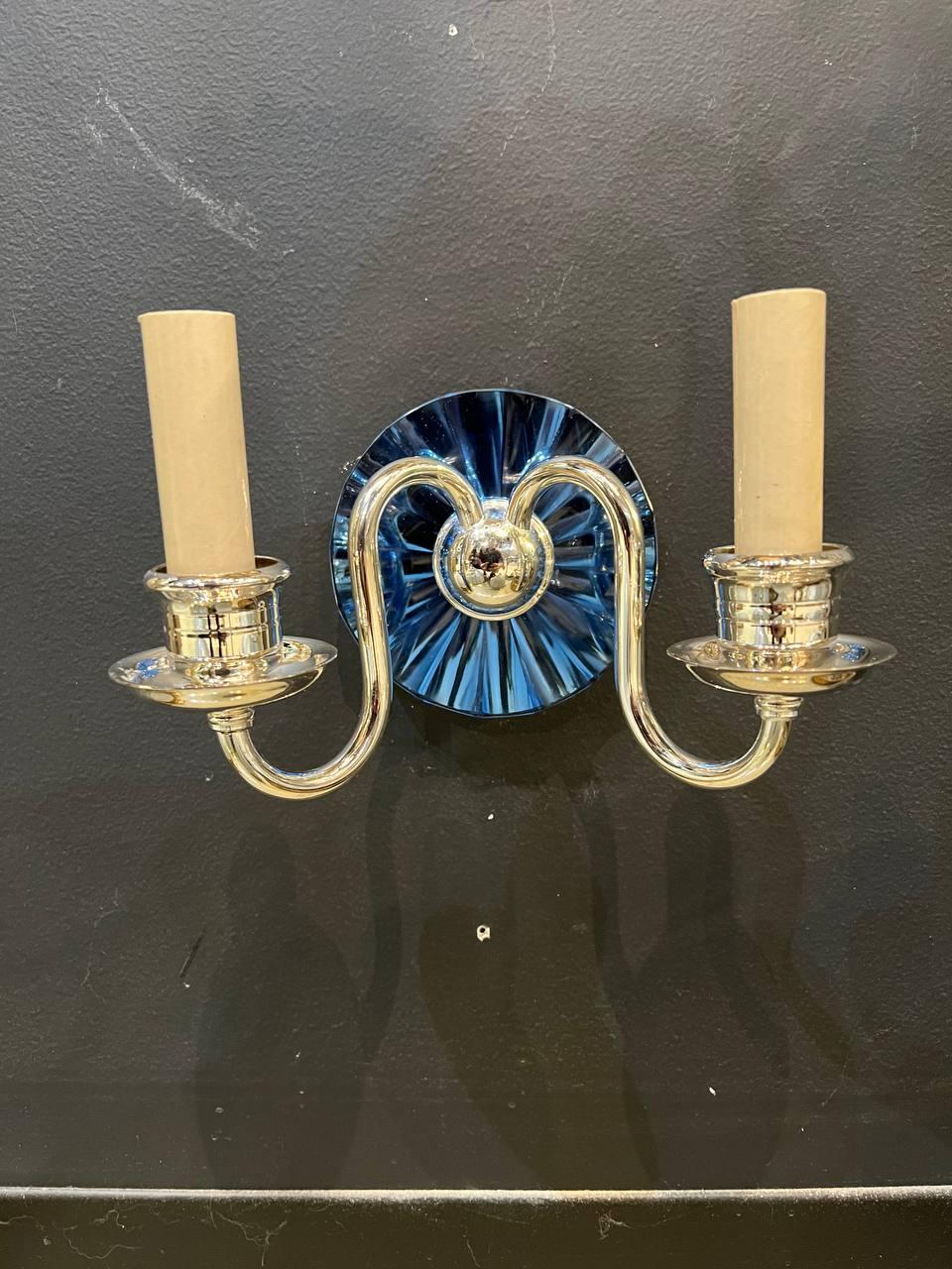 A pair of circa 1920's Caldwell double light silver plated sconces with cobalt mirrored backplate