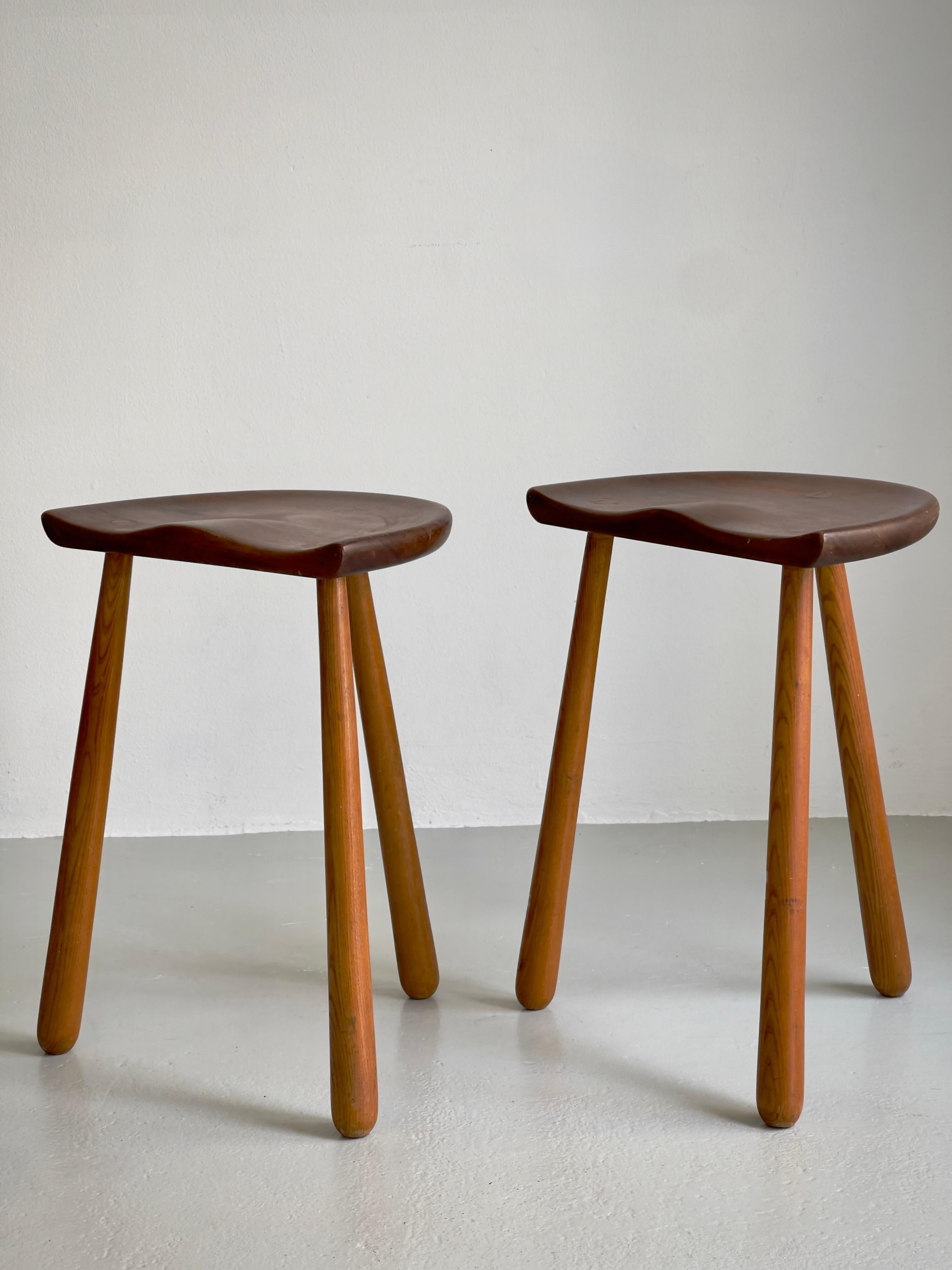 This finely crafted pair of 1940s Danish cabinetmaker stools exemplifies the sophisticated synthesis of sculptural form and ergonomic sensitivity that defined mid-century Scandinavian design. The hand-carved teak seats, with their gently scooped