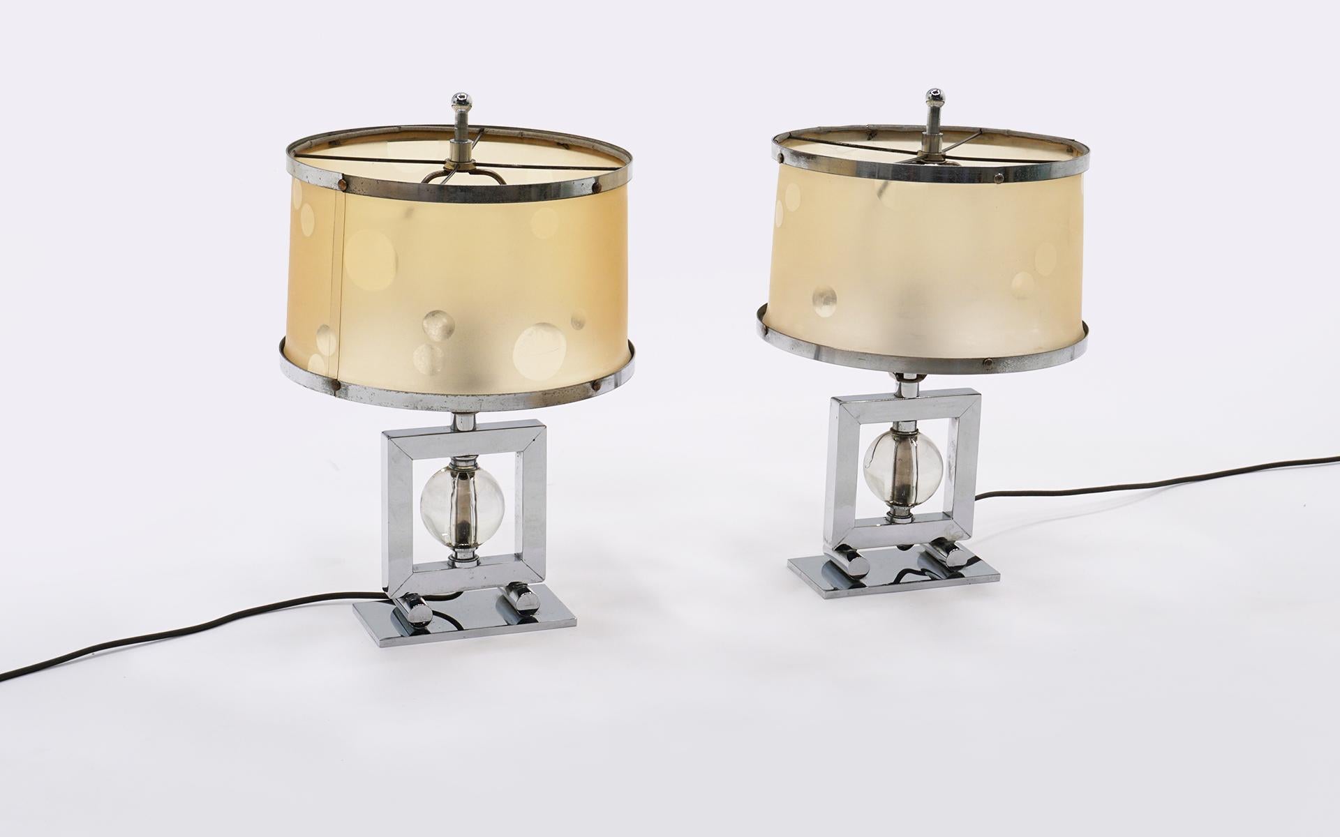 Rare pair of machine age table lamps. Chromed steel and glass. Awesome original shades with chrome trim. One shade has a one inch crack near the top that does not distract from the beauty of this highly desirable pair of lamps.