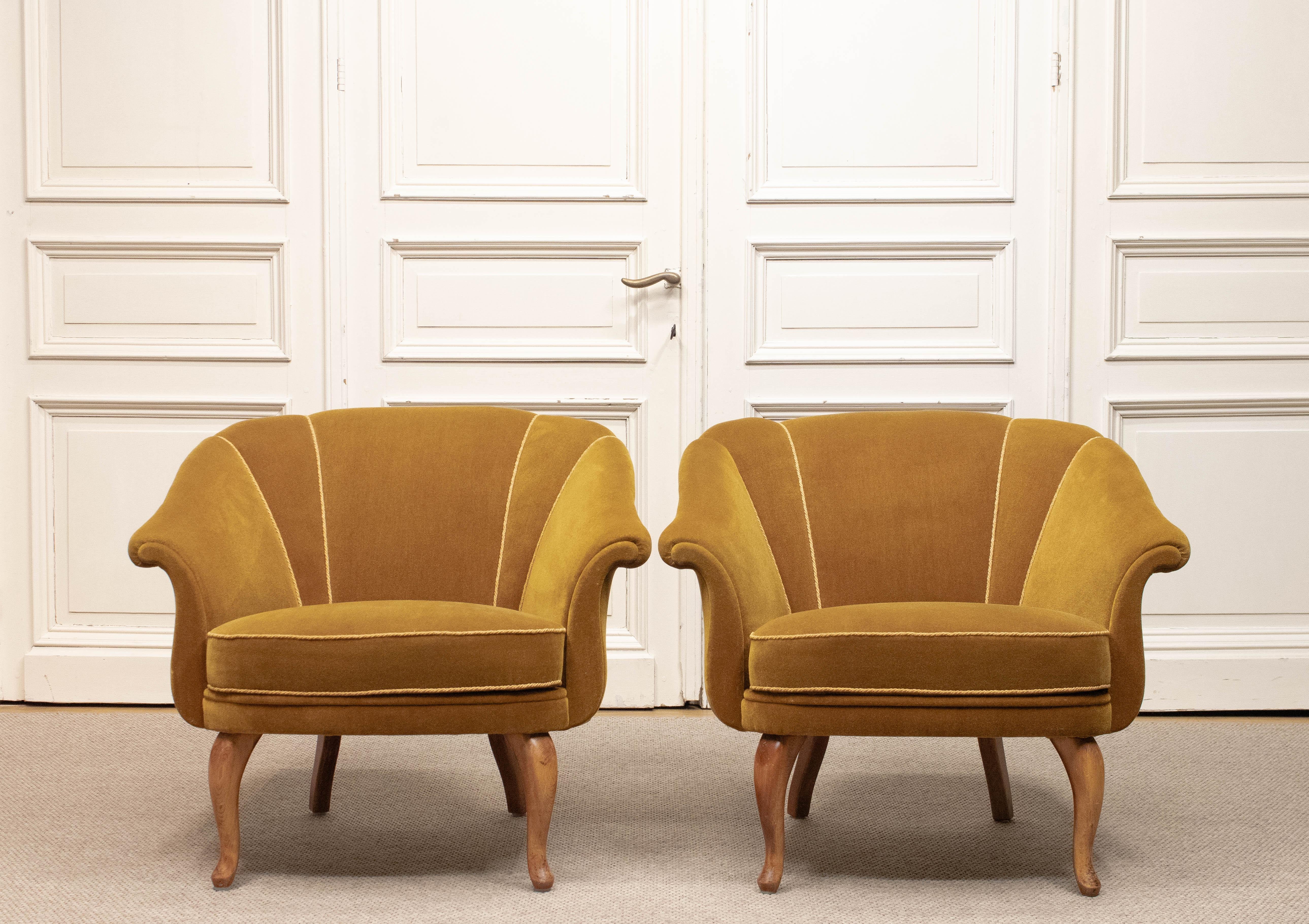 Ein Paar eleganter schwedischer Clubsessel aus den 1940er Jahren, wunderschön erhalten in ihrer ursprünglichen goldenen Samtpolsterung. Diese Sessel zeichnen sich durch eine unverwechselbare muschelförmige Rückenlehne aus, die sich anmutig nach