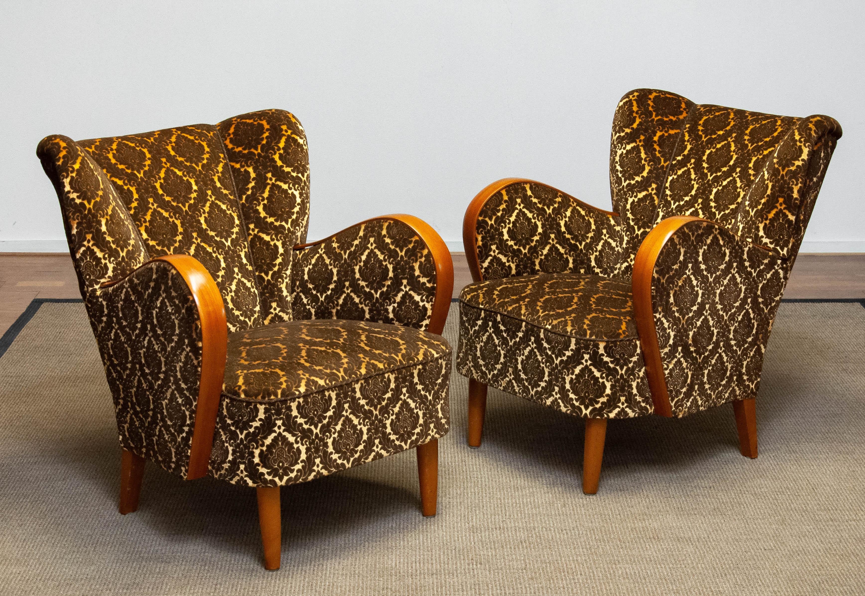 Absolutely beautiful and complete original pair Scandinavian lounge / club chairs in the style of Fritz Hansen made in Danmark.
Both lounge / club chairs are upholstered with gold and brown two tone jacquard velvet fabric. The bentwood armrests are