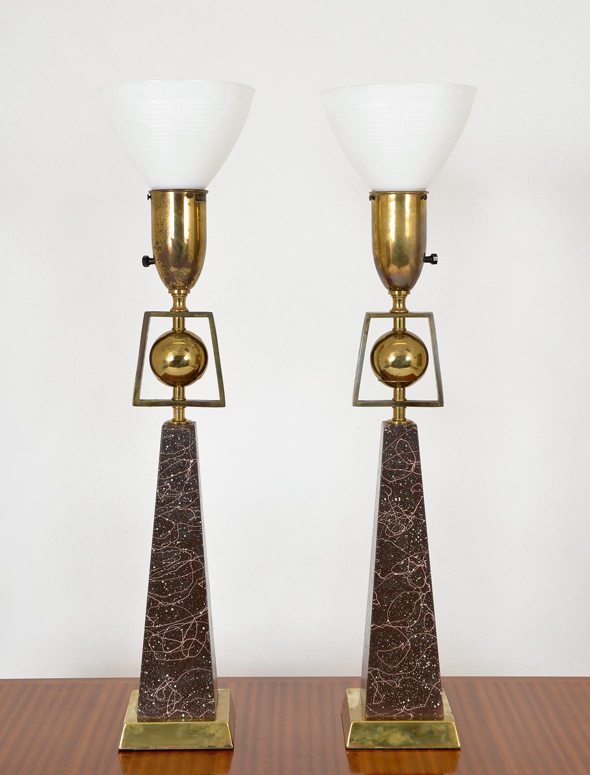 A pair of 1950s American Mid-Century Modern obelisk table lamps by Rembrandt Lighting, part of their ‘Masterpieces’ range. The lamps are in the form of an obelisk topped with a brass ball within a solid brass isosceles trapezoid frame, and