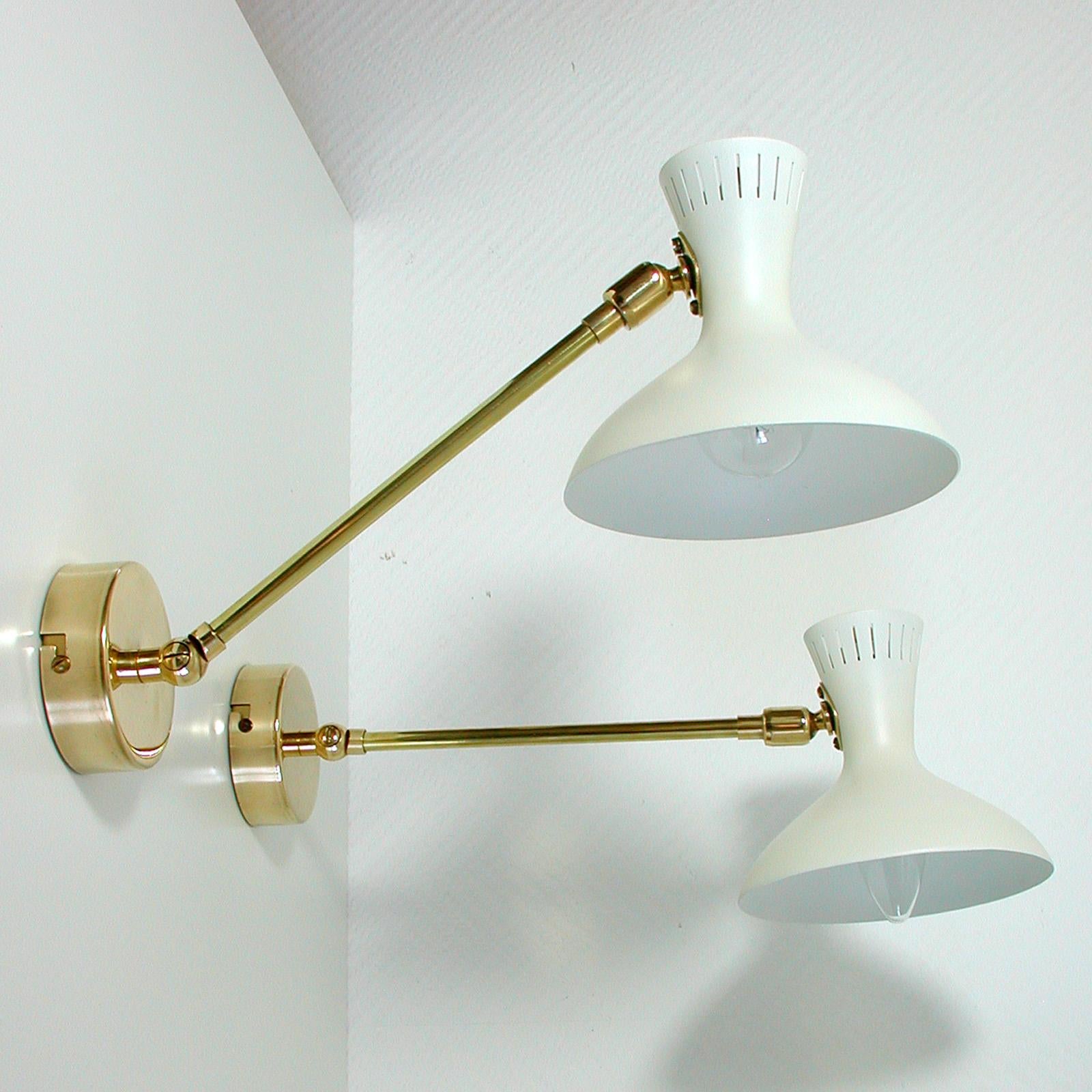 Very elegant pair of midcentury brass and white lacquered metal potence wall lights, made in France in the 1950s.

The sconces have got brass bases and adjustable brass articulating lamp arms. The shades are made of white lacquered metal.

The