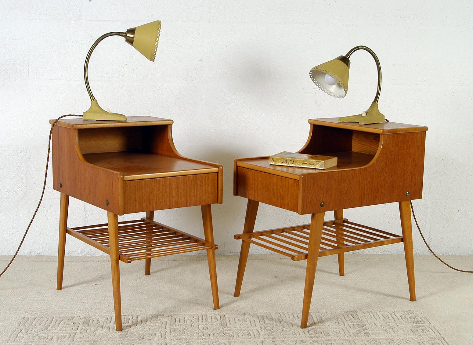A good matched pair of two tier Swedish Modern teak and beech nightstands, standing on beech legs with a single drawer and beech magazine rack beneath. They are both in very nice condition and show only the slightest signs of wear. Photographed with