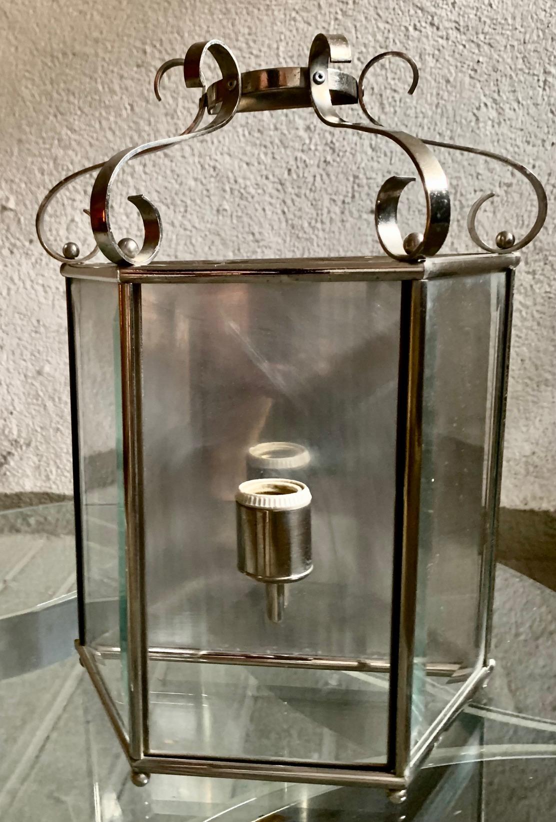 Pair of Spanish wall sconces, in chromed metal and beveled glass, from the 1960s, trapezoidal shape, the upper part in curved metal, the lower part ends in small balls.