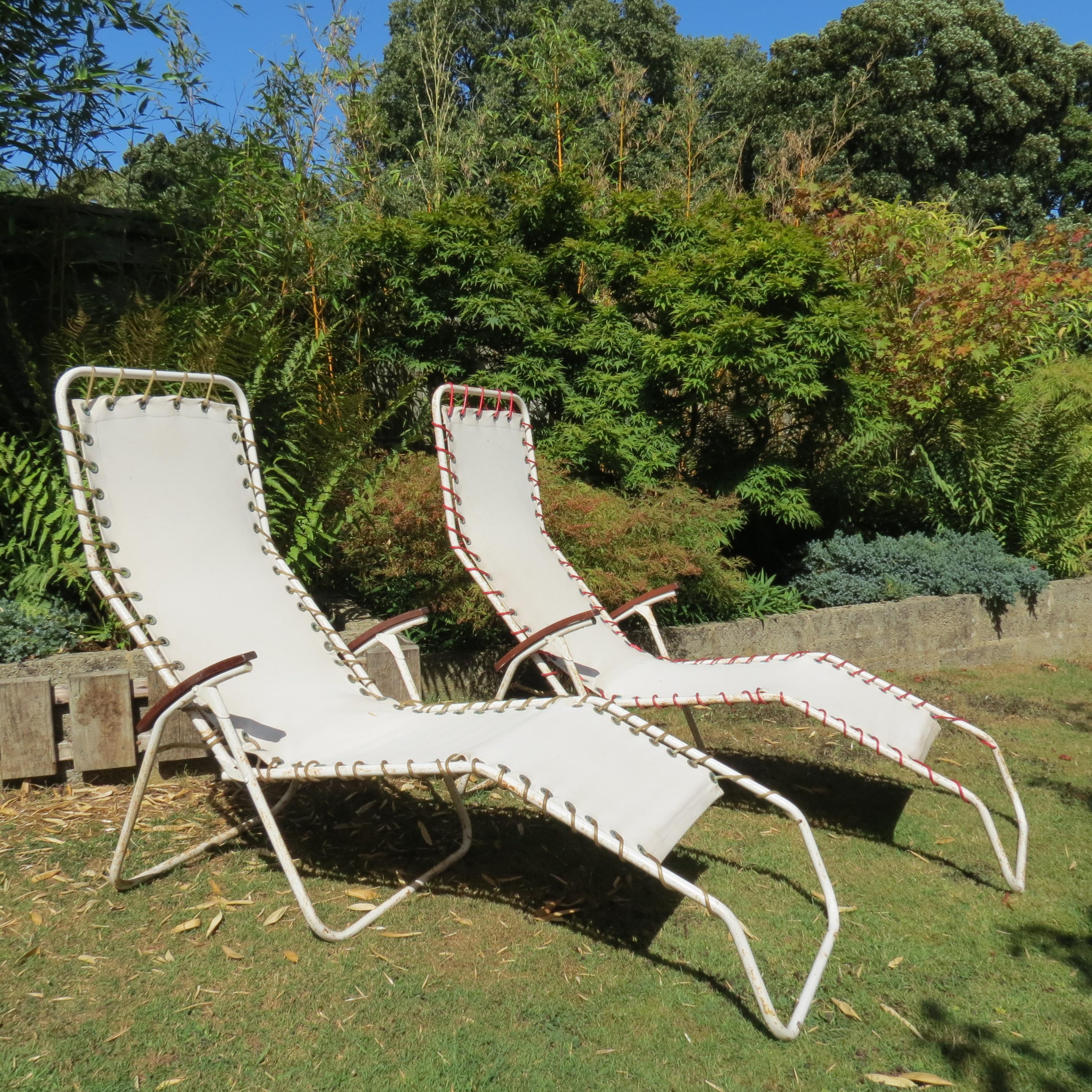 Wonderful pair of original 1970s garden lounge chairs. Metal tubular frames with distressed paint finish. Canvas seats attach to the frame with nylon cord. One of the nylon cords that attaches the seat sling to the frame has been replaced with a red